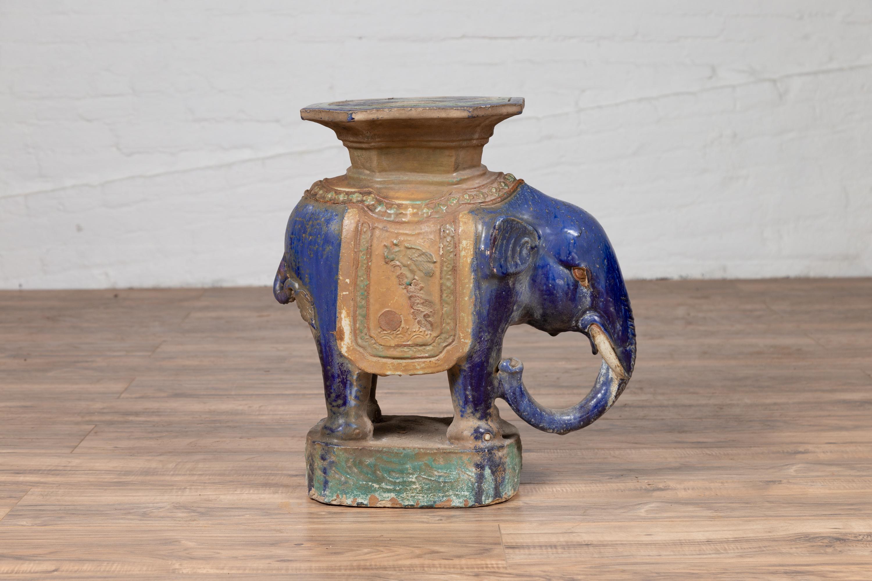 A Vietnamese Annamese multicolored garden seat from the early 20th century, depicting a cobalt blue elephant supporting a stool. Made of ceramic and hand painted in Annam, Vietnam, this lovely garden stool adopts an elephant shape and is covered