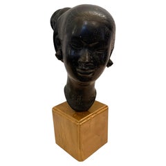 Escultura de una cabeza de mujer vietnamita en hierro fundido sobre una base de madera dorada, atribuida a Nguyen