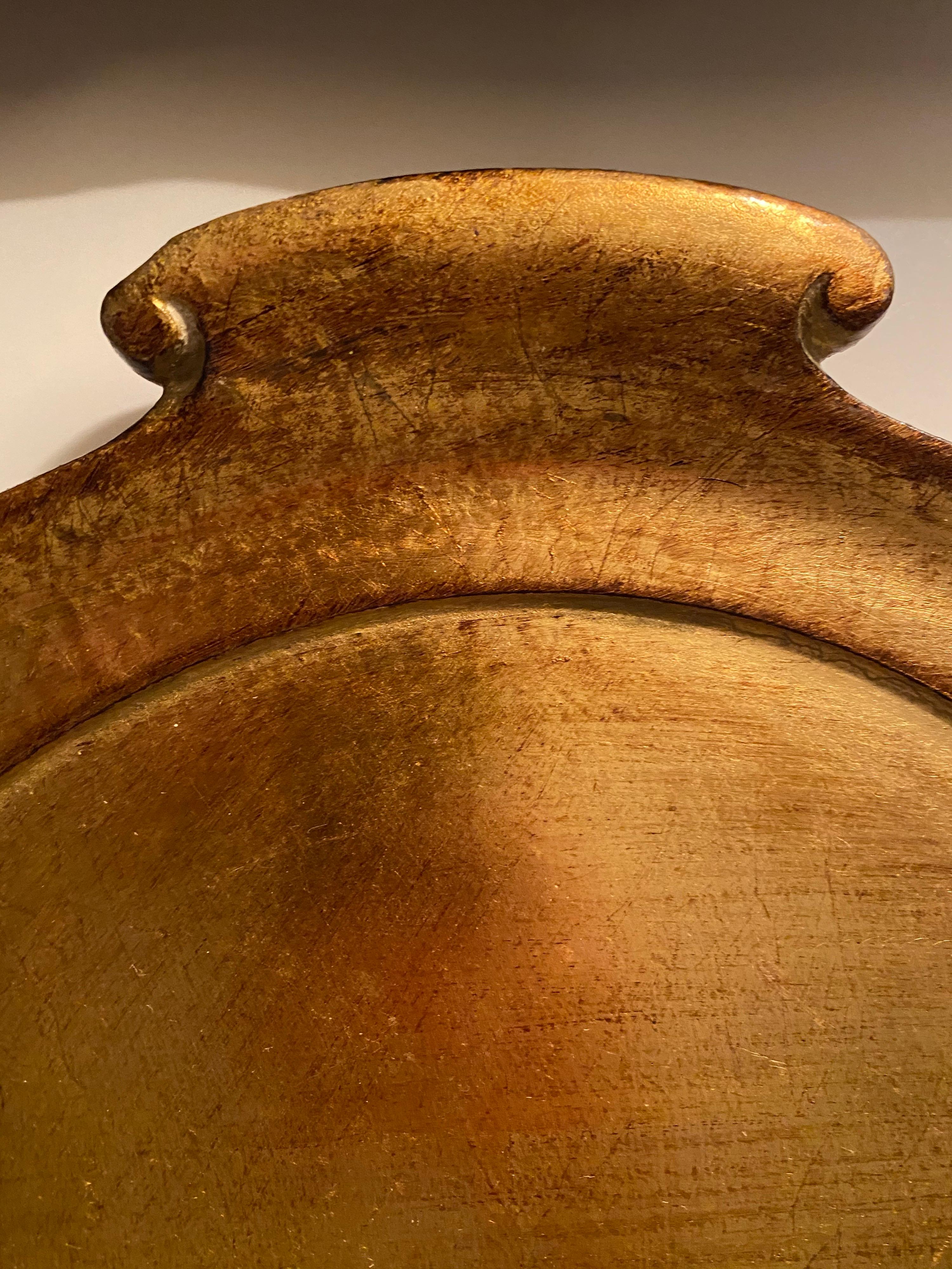 A gold leaf wood serving tray with handles by Vietri. Made in Italy, circa 2010.

Maestro artisans handcarve each beautiful curve of the Florentine Wooden Accessories Handled Medium Oval Tray before applying a signature gold leaf. This timeless