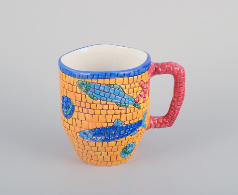 Vietri, Italy. Set of four large mugs and a large pitcher in ceramic. 
Decorated with fish and sea motifs in a mosaic-like pattern.
Late 20th century.
Marked.
In excellent condition with minimal signs of use.
Mugs: Height 10.8 cm x Diameter 9.0 cm