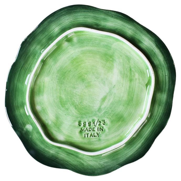 A round majolica ceramic plate by Vietri. Known as Foglia Leonardo, the round green ceramic majolica plate features a raised leaf motif throughout. Glazed in a variety of greens, this flat dish will be wonderful in any place setting.