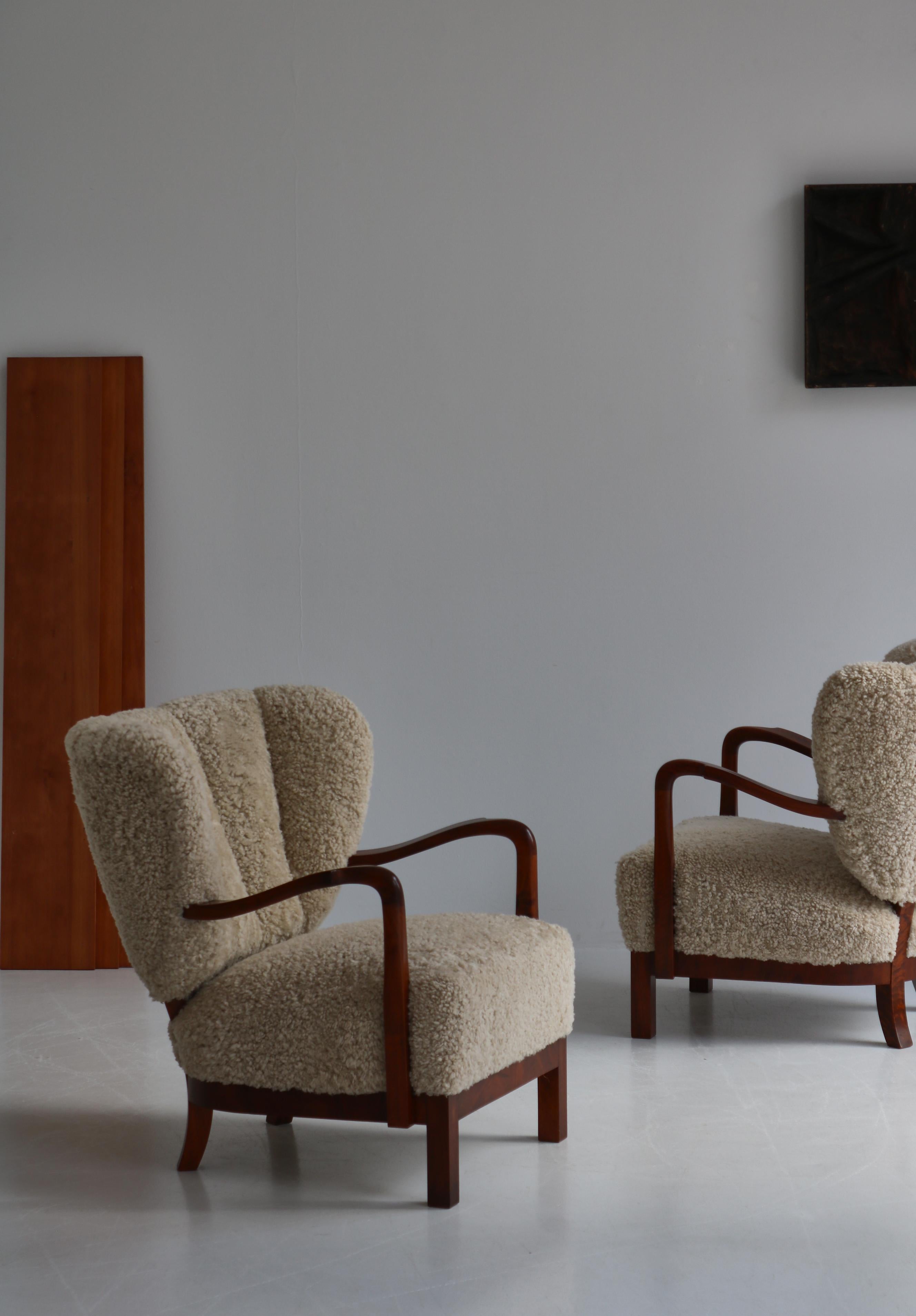 Absolutely amazing pair of 1930s Scandinavian Modern easy chairs attributed to Danish architect Viggo Boesen. The chairs are made from nutwood and has been reupholstered in beautiful natural sheepskin. They were most probably designed by Boesen in