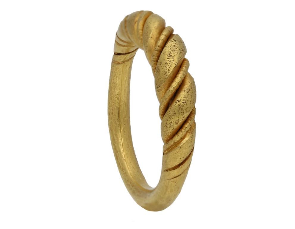 Ring aus Wikinger-Gold mit gedrehtem Drahtgeflecht. Ein Gelbgoldring, der aus einem schlanken Perlendraht besteht, der um einen dicken, gedrehten Goldstab gewickelt ist, der von der Mitte aus leicht abnimmt und sich zu einem massiven, abgerundeten