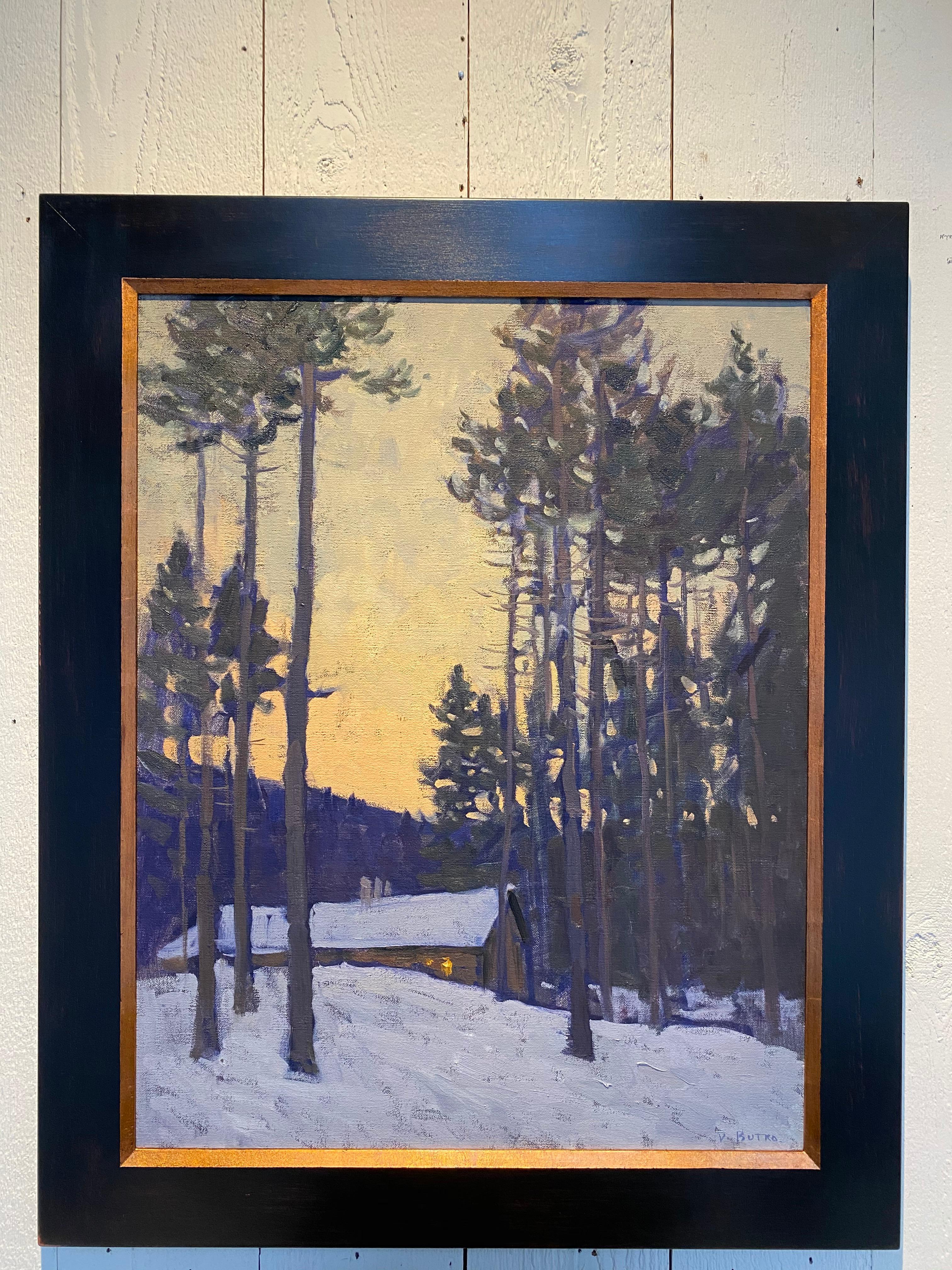 An oil painting of a lit cottage in the snowy woods. Painted en plein air, during quarantine for the Covid-19 outbreak, in February of 2020. This sugar shack is backlit from the yellow orange sunset above. Tall trees flank each side of the