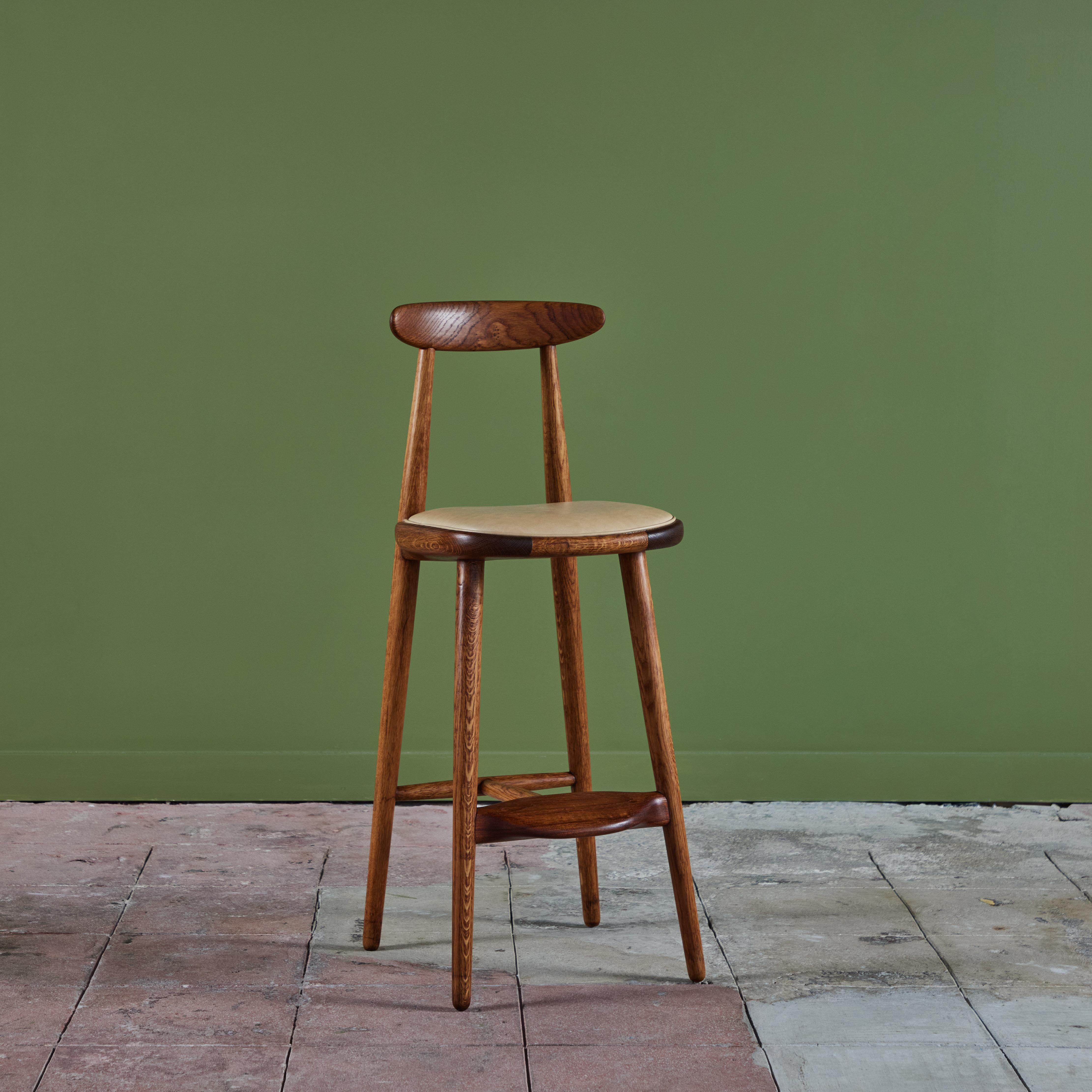 Bar stool by Vilhelm Wohert for Stolefabriken Odense, c.1950s Denmark. This bar height stool features a newly upholstered leather seat. The stool also features teak and oak frame with foot rest.  
We have three stools available, priced