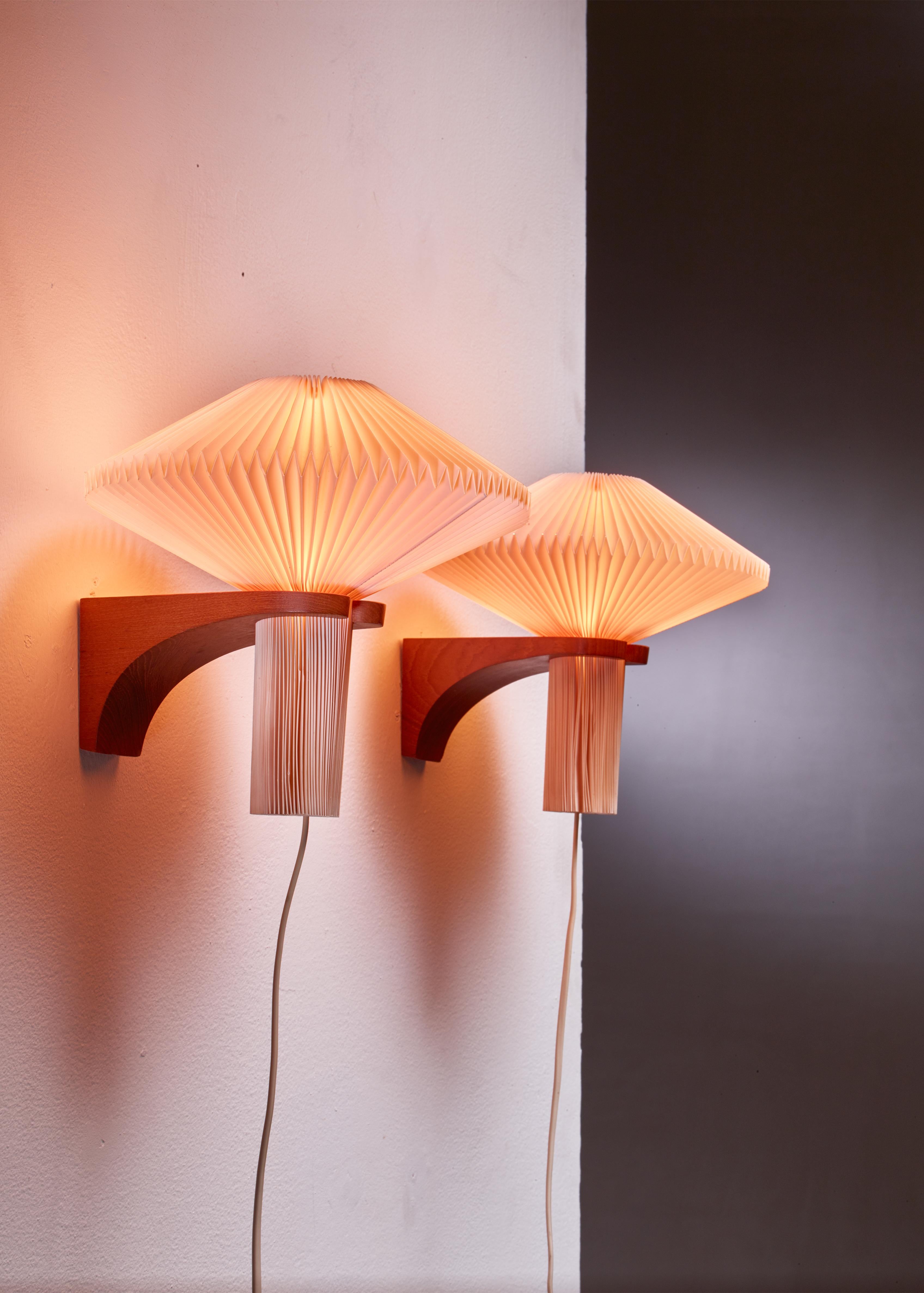 A pair of model 204 wall lamps by Vilhelm Wohlert. The lamps have a teak wall mount, holding a pleated plastic Le Klint shade.

The lamp was designed in 1957 for Niels Bohr's summer house.