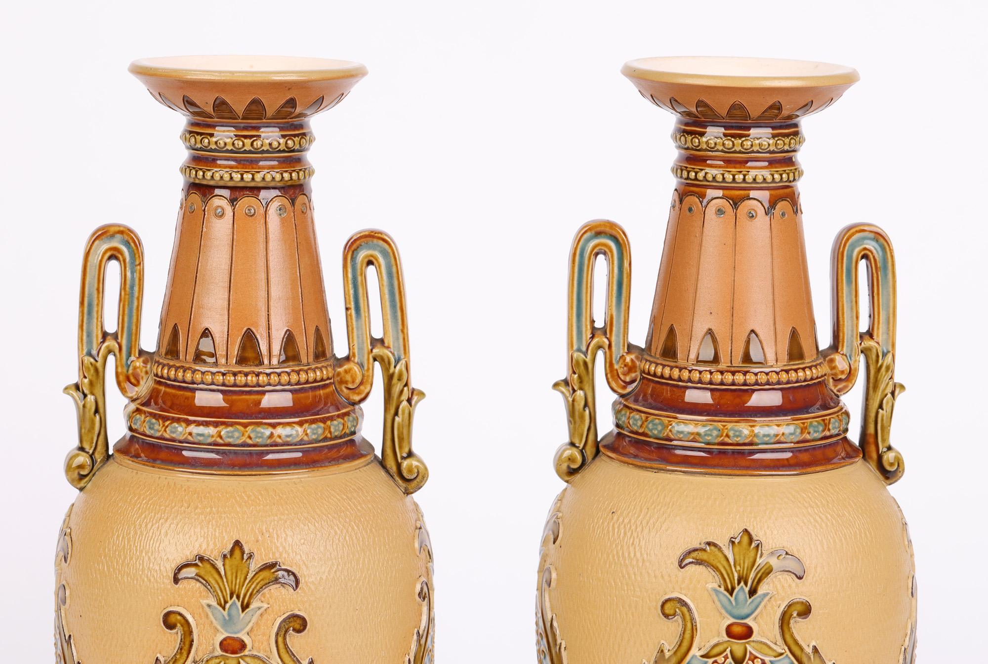 A stunning and large pair German Villeroy Boch Mettlach Art Nouveau twin handled vases of tall slender shape with stylized floral designs dating from around 1900. The vases stand on a rounded pedestal foot with the slender bulbous shaped bodies with