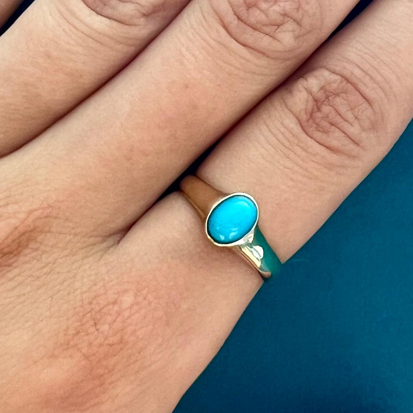 A lovely turquoise ring set in a gold band. The turquoise stone is oval shaped and set in a high polished 14 karat gold frame. The gold of the ring has a small openwork design on both sides of the stone. It is said that turquoise connect heaven and