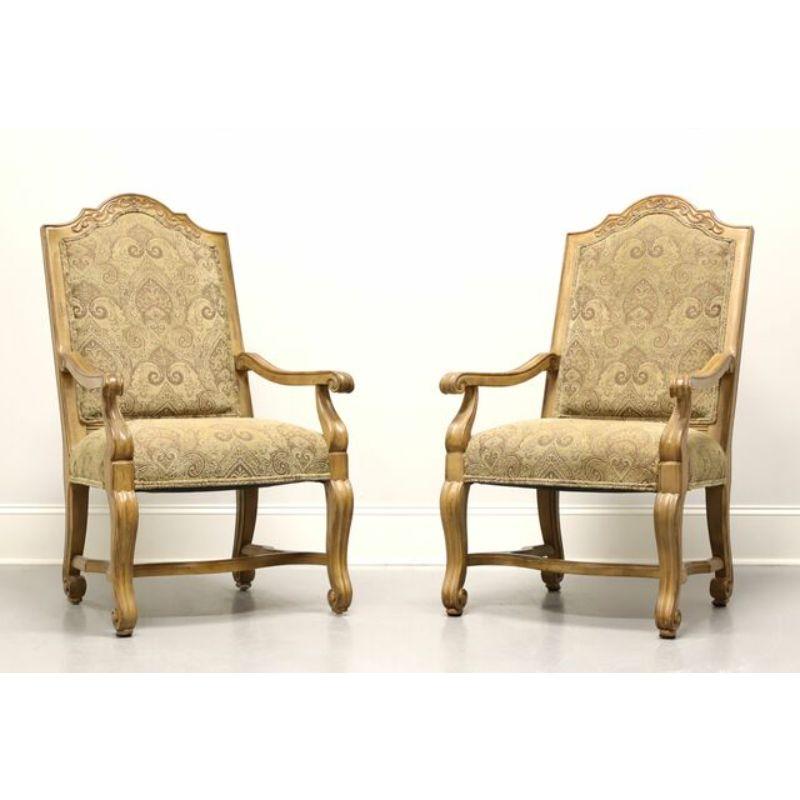 A pair of Rustic Italian style dining armchairs by Bernhardt Furniture. Solid wood frames with a distressed finish. Arched top to seat backs, carved curved arms and legs with a stretcher base. The high seat backs are upholstered with a tapestry like
