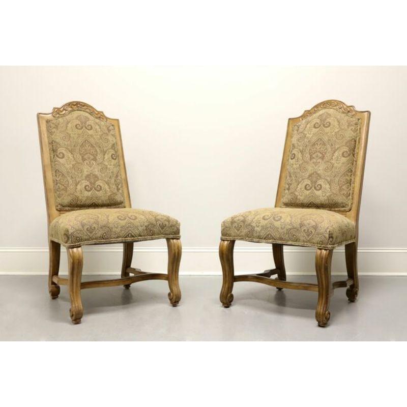 A pair of Rustic Italian style dining side chairs by Bernhardt Furniture. Solid wood frames with a distressed finish. Arched top to seat backs, carved curved legs and stretcher base. The high seat backs are upholstered with a tapestry like raised
