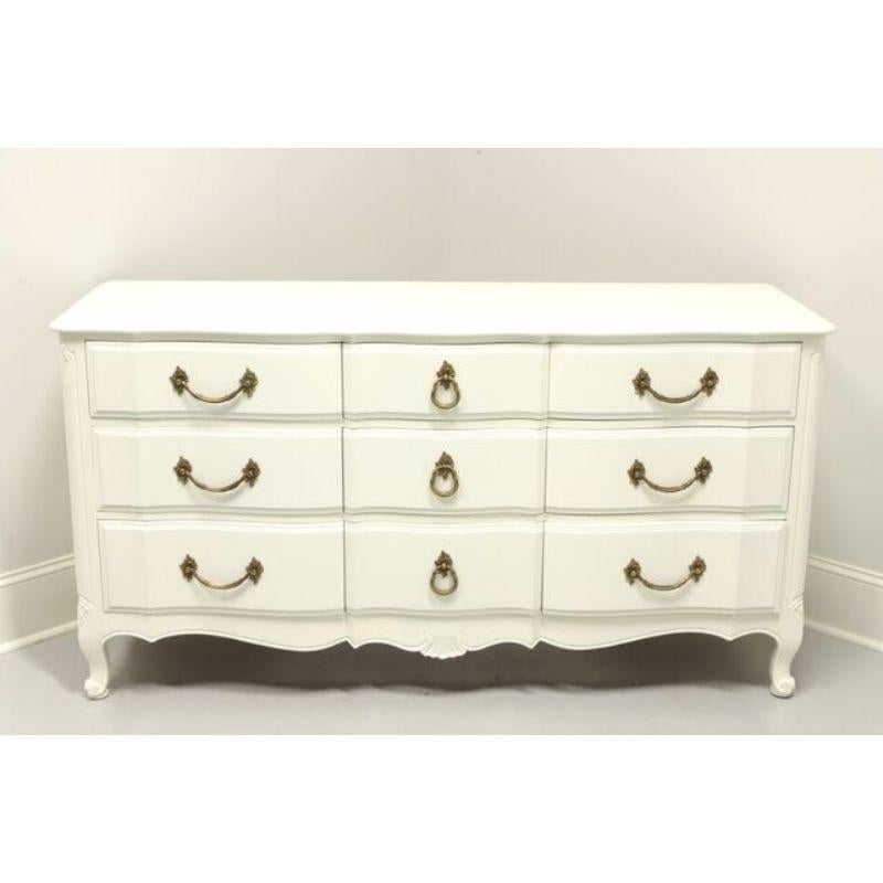 A French Country style triple dresser by Davis Cabinet Co, of Nashville, Tennessee, USA. Cherry wood, freshly updated with cream colored paint, metal hardware, curved front, carvings to sides and feet. Features nine drawers of dovetail construction,