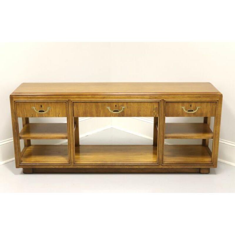 A Campaign style console table, or alternatively a media stand, by Drexel Heritage. Solid oak with brass hardware. Features three dovetail drawers with faux lockplates over an undertier with two open side shelves. Made in Drexel, North Carolina,