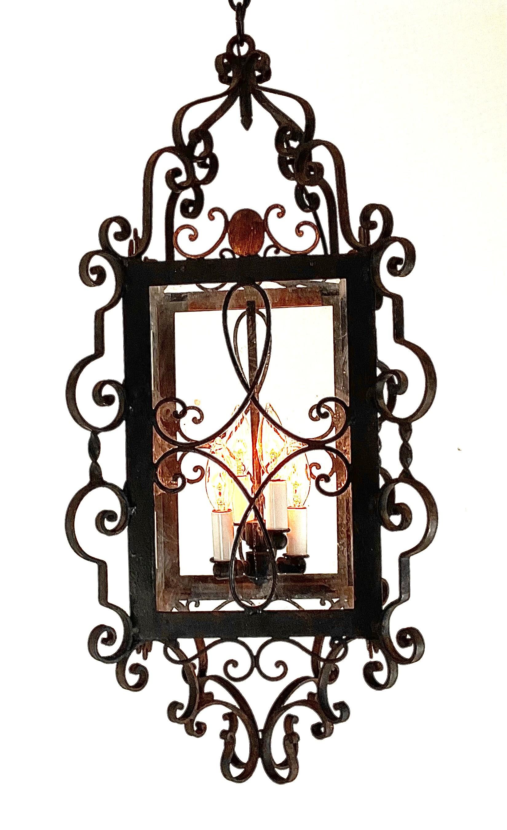 Elevate any interior with this striking vintage wrought iron lantern, richly detailed with ornate hand-forged scrollwork. Its architectural silhouette is framed by an elegant array of symmetrical curves, giving the piece a refined Old-World presence