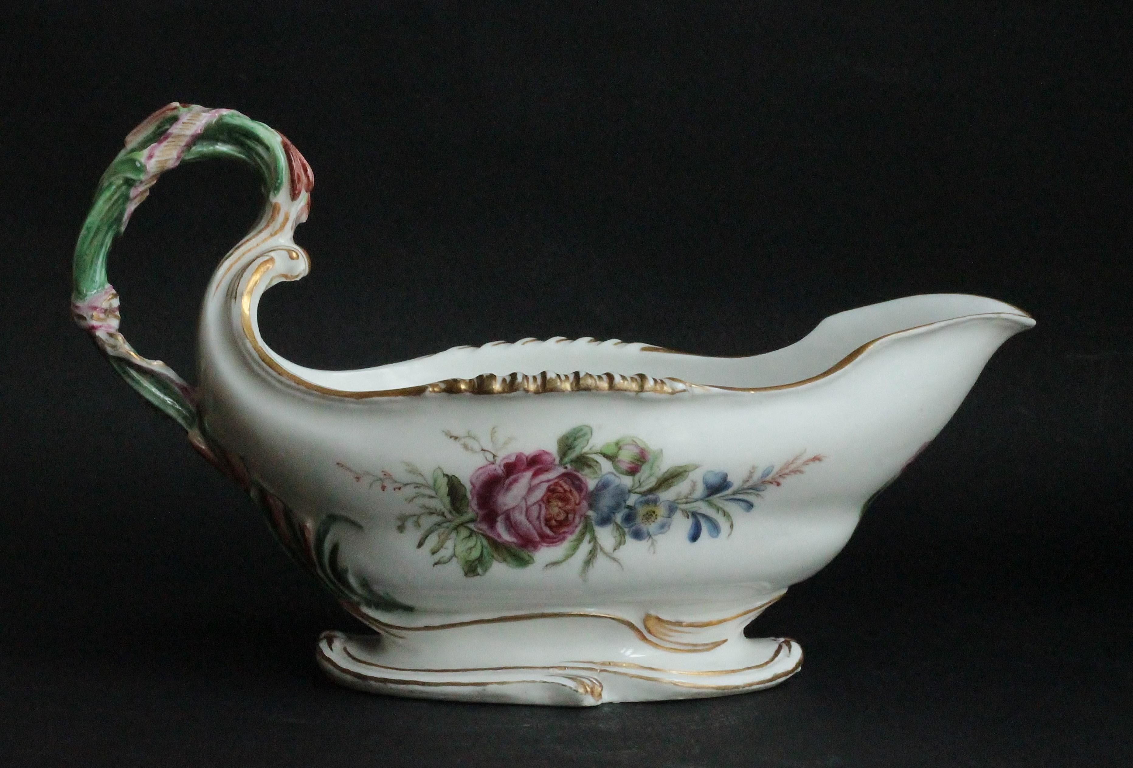 A sauceboat in Vincennes porcelain. The scrolling edges picked out in gold, the handle modelled as a bush of reeds held together by a ribbon in gold, decorated on either side with floral sprays, two single flowers to the front.
Measures: Depth: 11