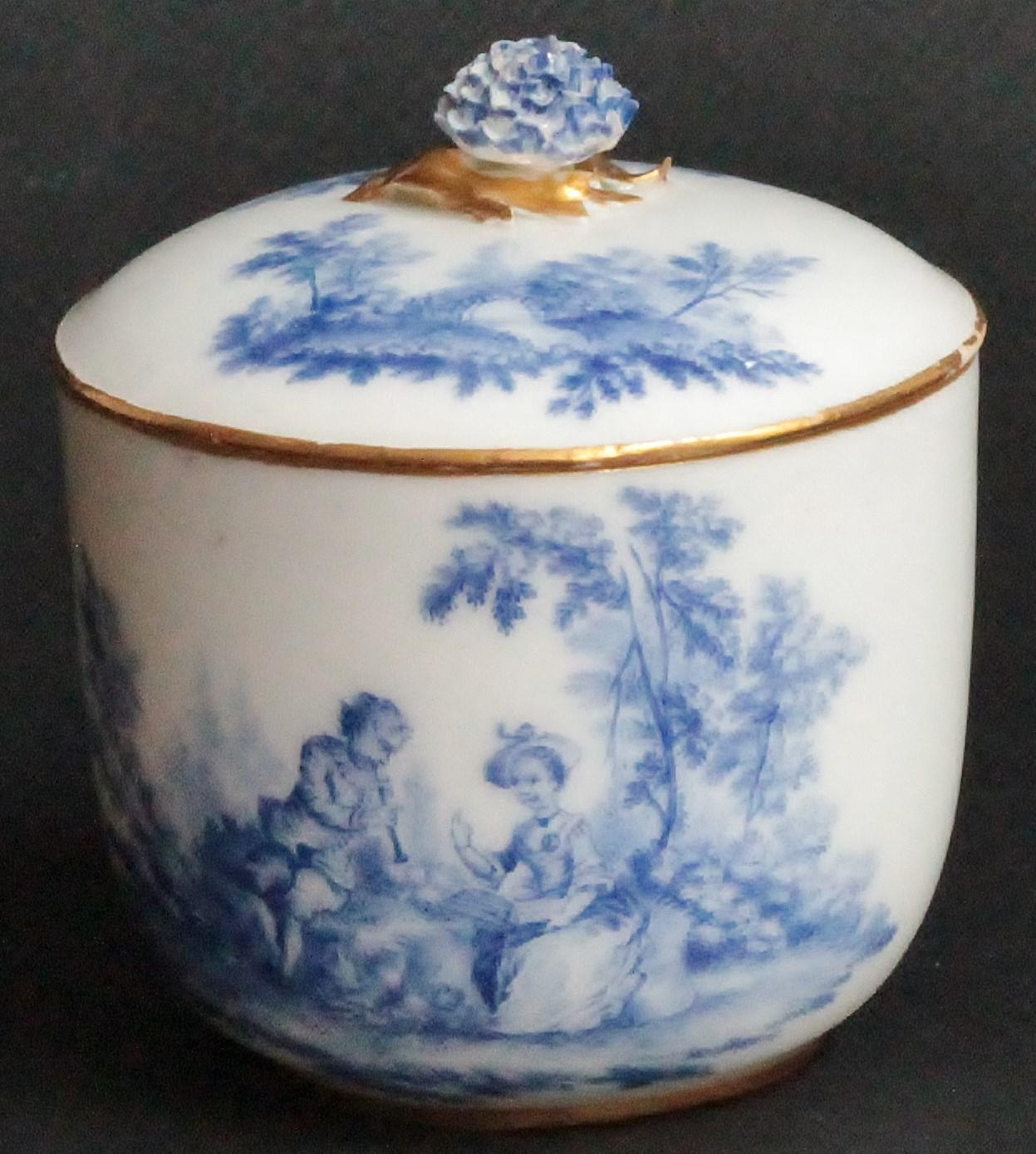 A Vincennes sugar bowl and cover, circa 1752.
Pot à sucre ‘Calabre’ of the first size, painted with blue shades vignettes of couples seated in landscapes, the cover similarly decorated and applied with a flower finial, gilt borders to the