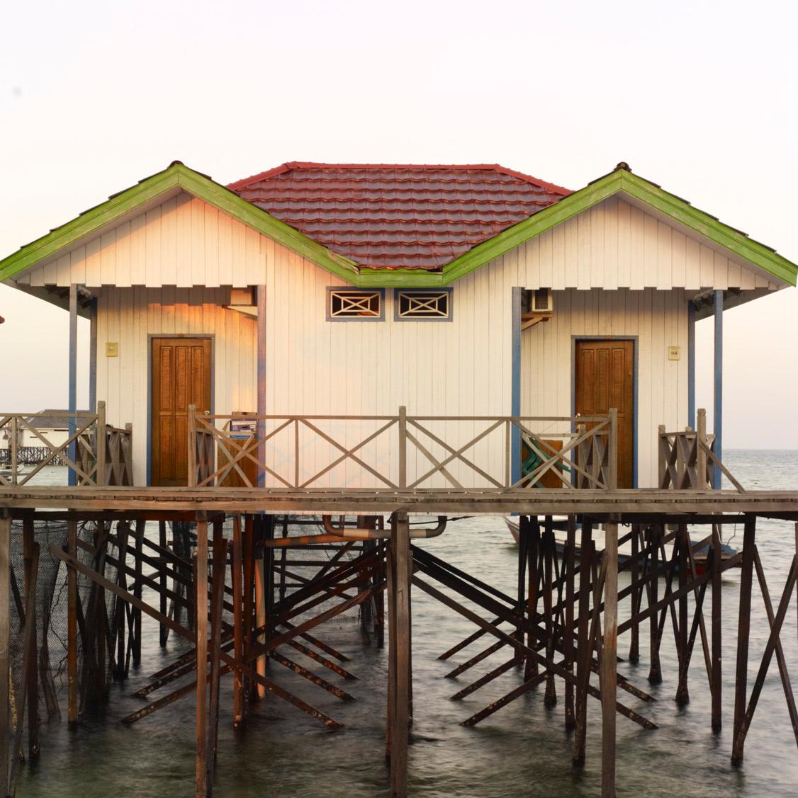 Borneo 1: stilt house architecture in water landscape at sunrise, Southeast Asia - Photograph by Vincent Dixon