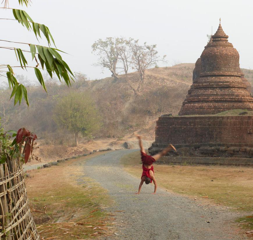 Myanmar 1: child Buddhist monk playing by Southeast Asia temple landscape - Photograph by Vincent Dixon