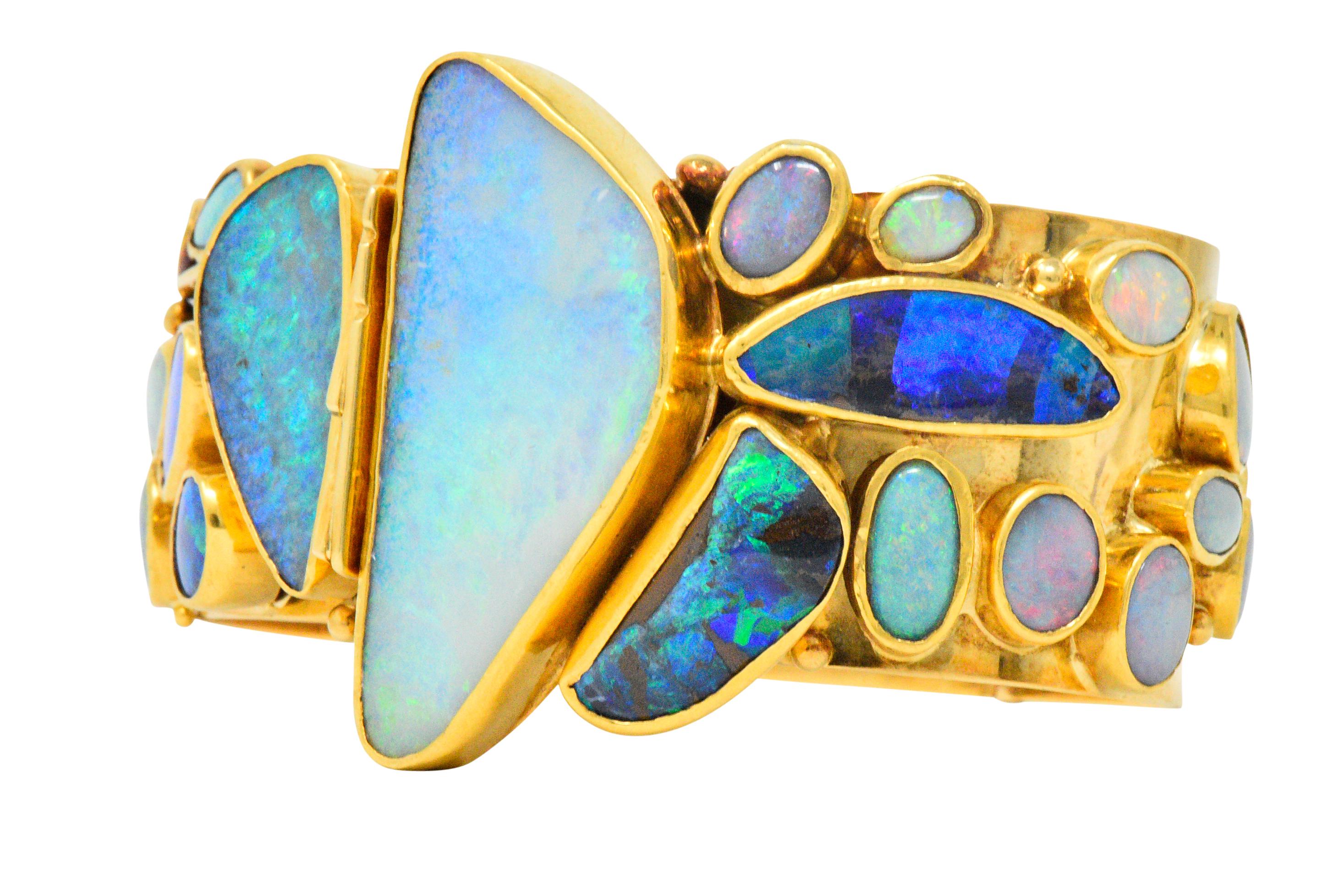 Wide hinged bangle set to the front with various cut polished opals, including white, black and grey, all with very good play-of-color

All opals applied and bezel set

Concealed clasp at the front between the two larges opals

Signed V. Ferrini