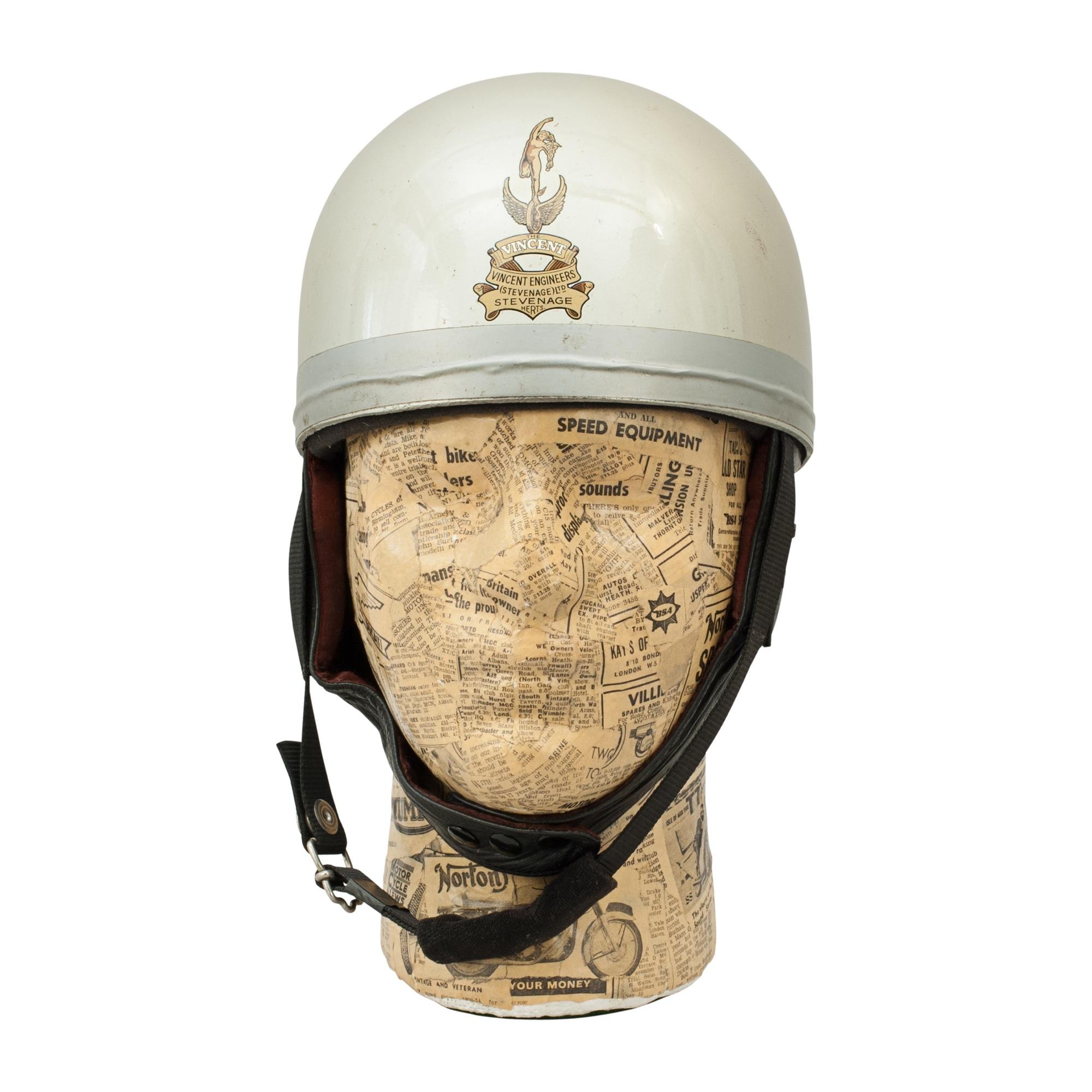 A grey painted motorcycle, Pudding basin shape helmet made in England by Charles Owen. There are decals on the helmet, Vincent of Stevenage on the front and Everoak on the back. This helmet has a cork interior, fitted with a fabric headband and