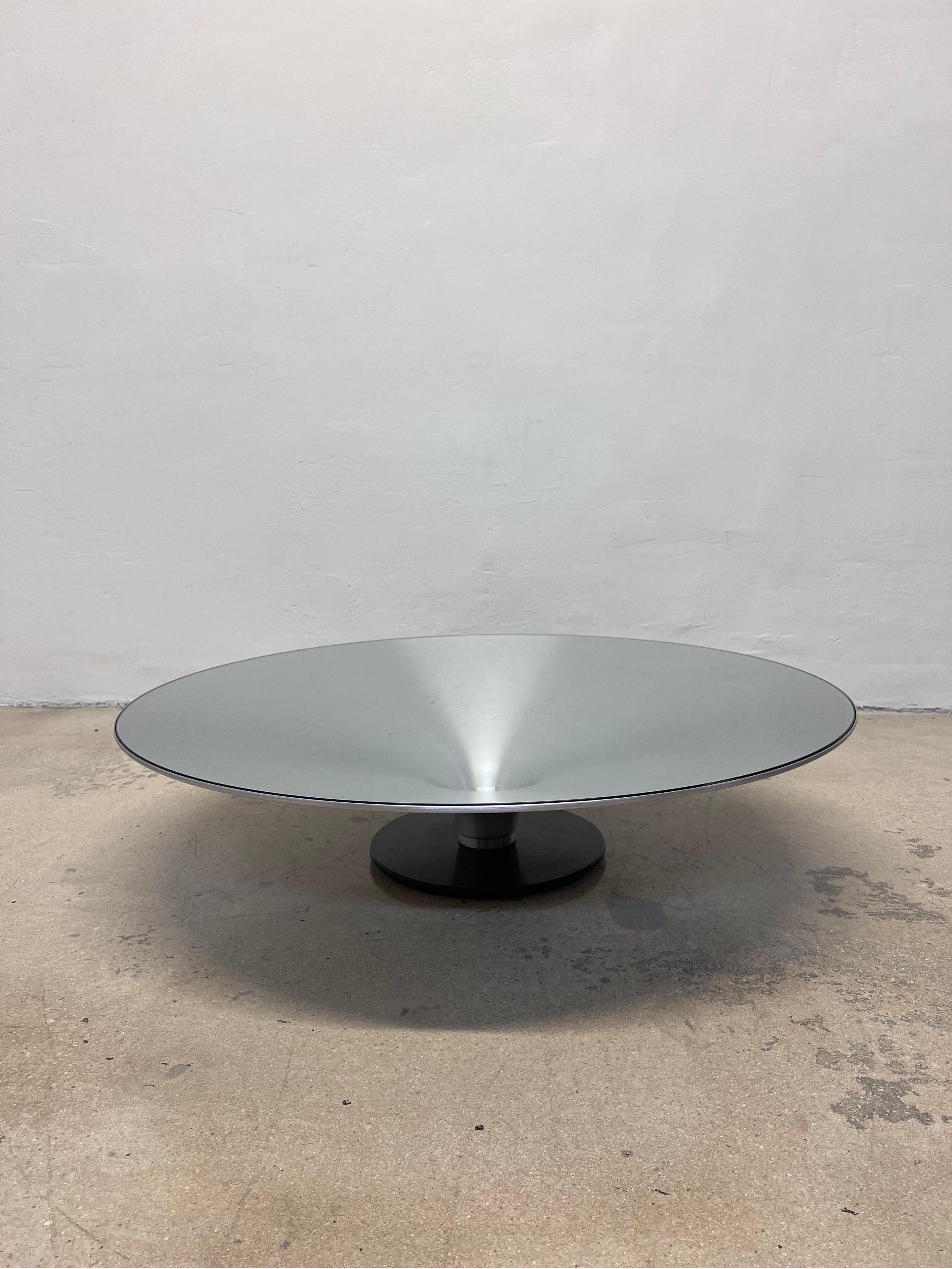 Roche Bobois low OVNI ø.90 cocktail table designed by Vincenzo Maiolino. The steel base has a black matte finish while the aluminum cone table structure is natural with a clear coat varnish to protect the finish. The clear glass is 6mm thick,
