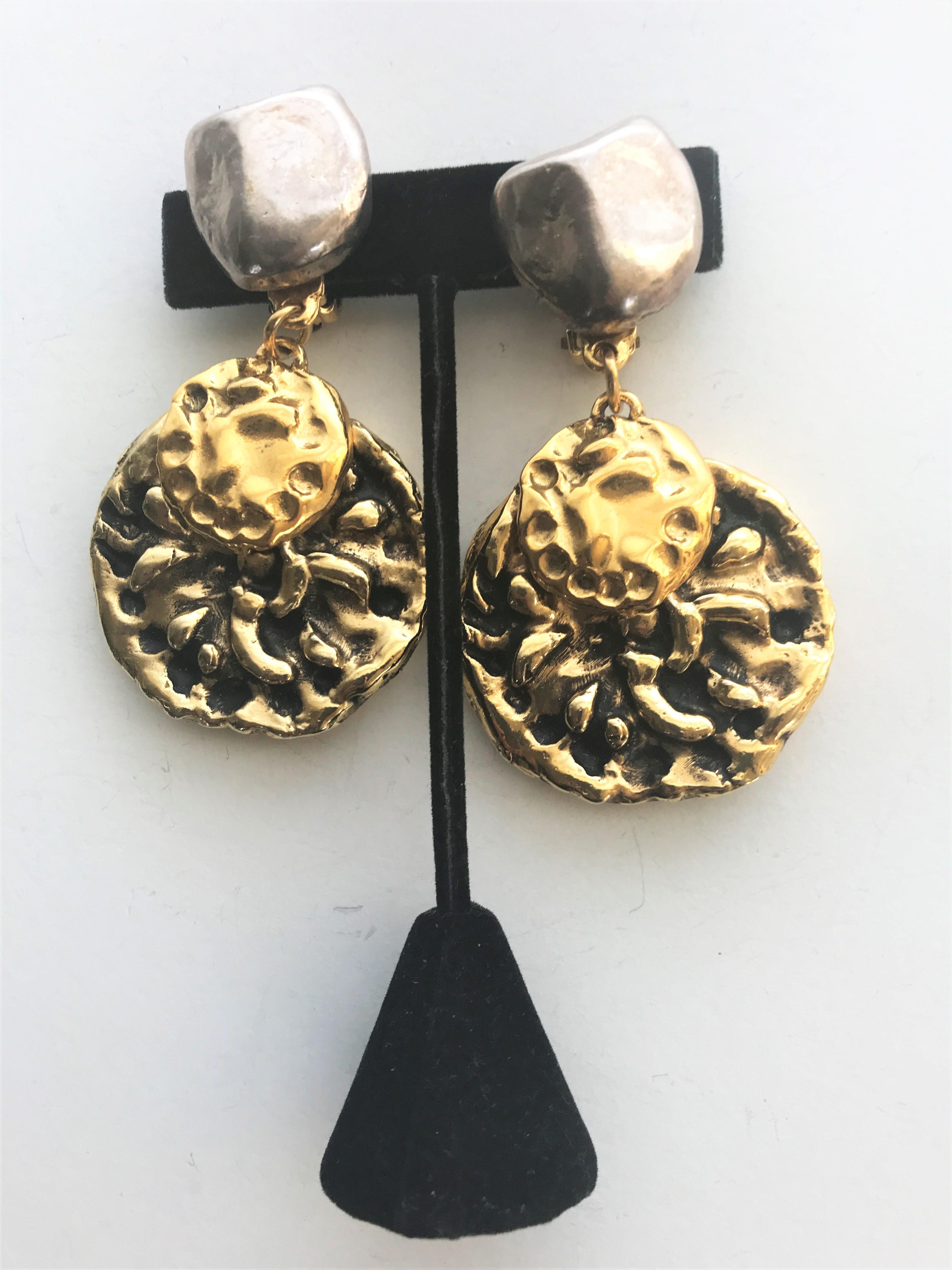 Very decorative clip-on earrings signed YSL. The upper part is made of pressed silver metal and looks like a Y. On the back you find the signature. The medallion attached is gold and black typical for YSL. Very distinctive color and material