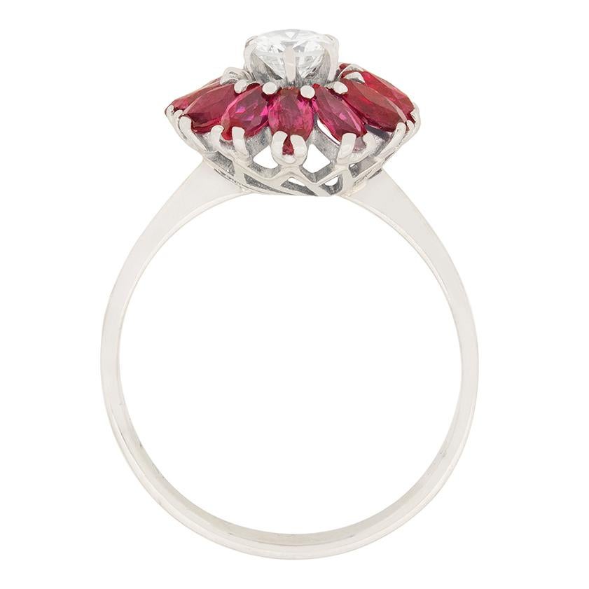 A 0.40 carat diamond is surrounded by a halo of marquise cut rubies. The diamond is graded as I colour and VS2 clarity. The rubies total to 1.20 carat, and have a deep red colour. All the stones are claw set in 18 carat white gold. The band is also