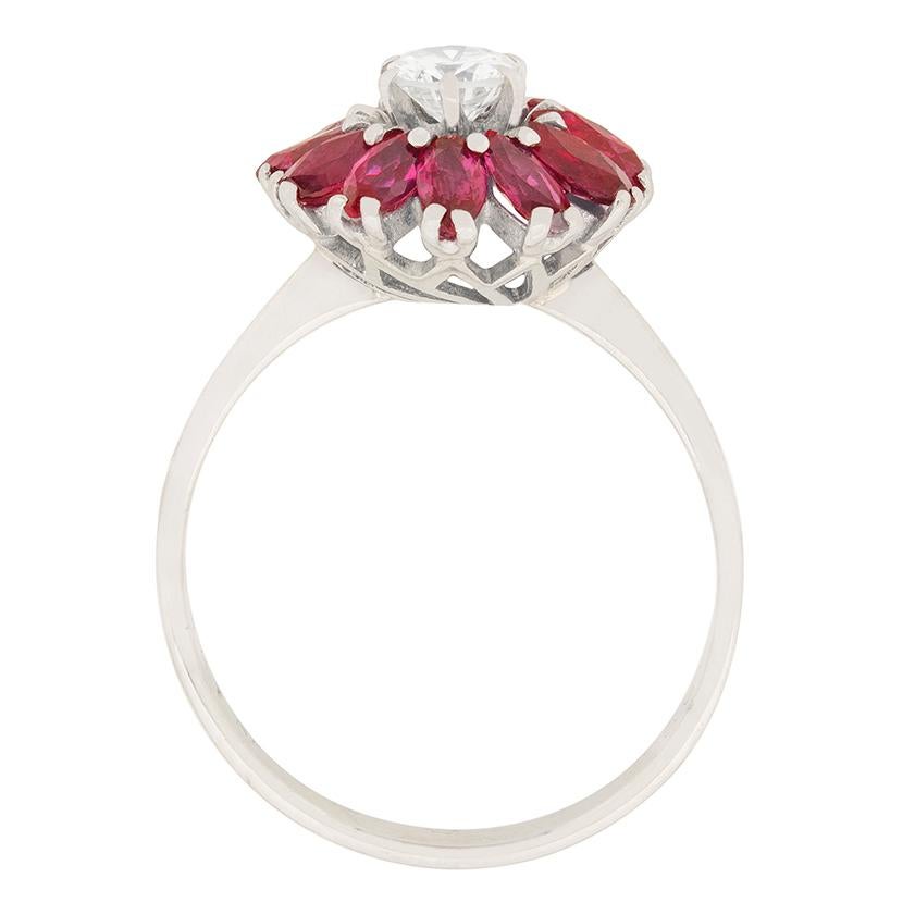Ein Diamant von 0,40 Karat ist von einem Halo aus Rubinen im Marquiseschliff umgeben. Der Diamant ist mit der Farbe I und der Reinheit VS2 eingestuft. Die Rubine haben ein Gesamtgewicht von 1,20 Karat und eine tiefrote Farbe. Alle Steine sind in 18