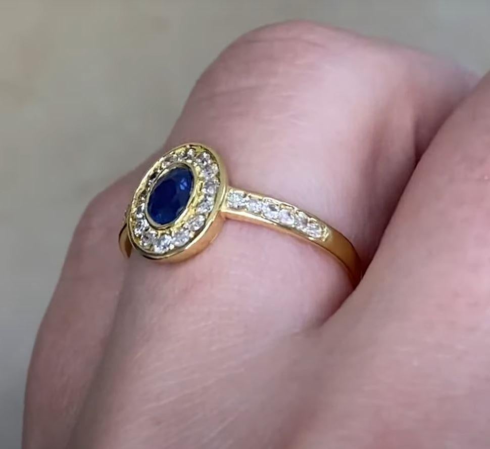 This exquisite vintage French ring showcases a stunning approx. 0.4-carat oval-cut sapphire at its center, elegantly bezel-set for a timeless appeal. Surrounding the sapphire is a delicate halo of round brilliant-cut diamonds, enhancing its