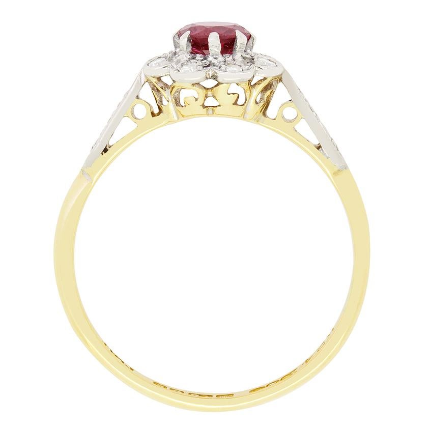 Questo anello a grappolo degli anni '60 è incentrato su un singolo rubino rosso. La pietra dal taglio rotondo di 0,40 carati è circondata da un anello di diamanti bianchi che fanno risaltare il colore del rubino. Gli otto diamanti tagliati ammontano