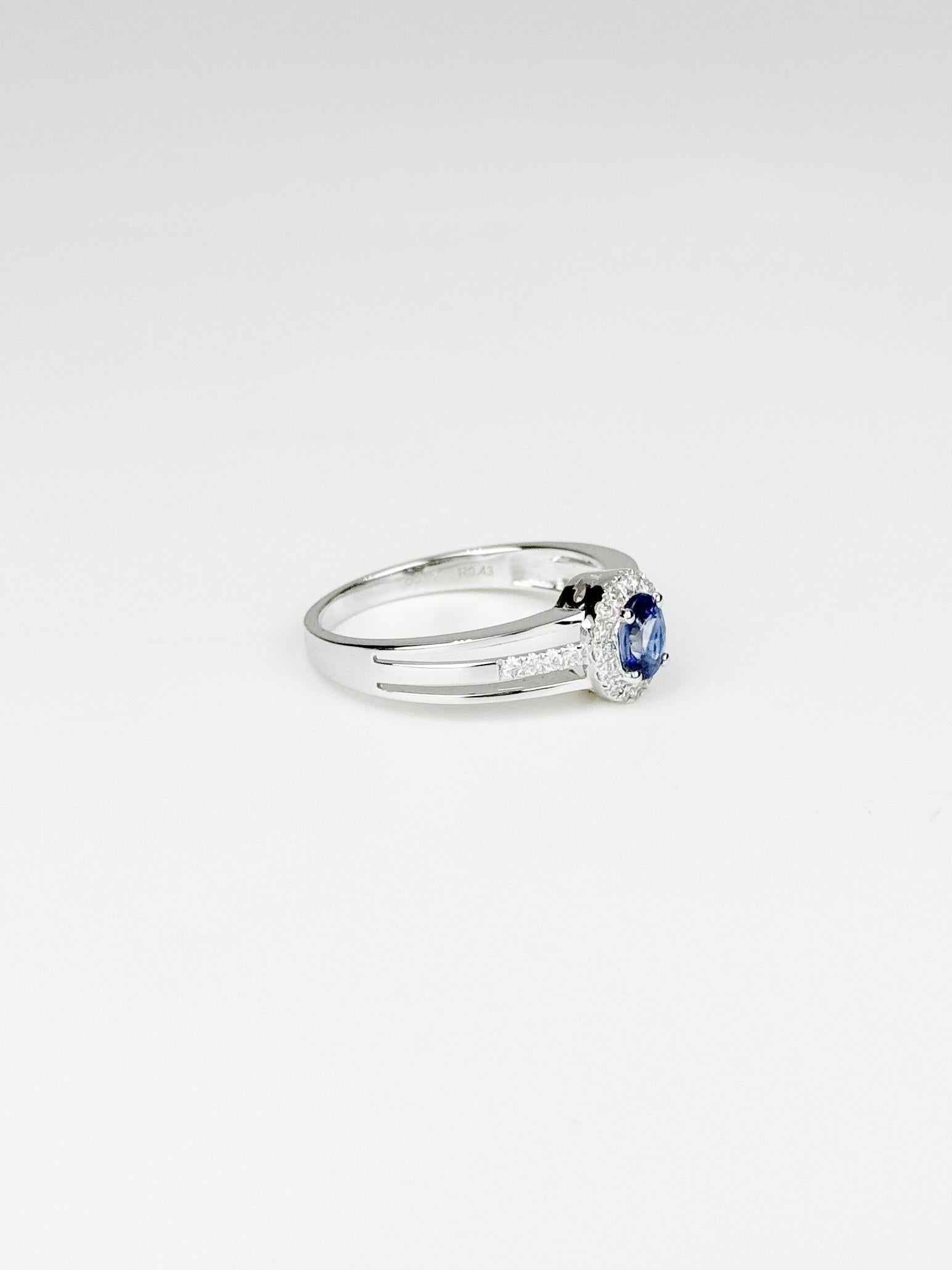 This stunning ring, crafted in 18K white gold, features a captivating 0.43 carat Sri Lankan sapphire as its centerpiece. The sapphire's vivid blue hue is perfectly complemented by a halo of sparkling diamonds, totaling 0.17 carats, which enhance the