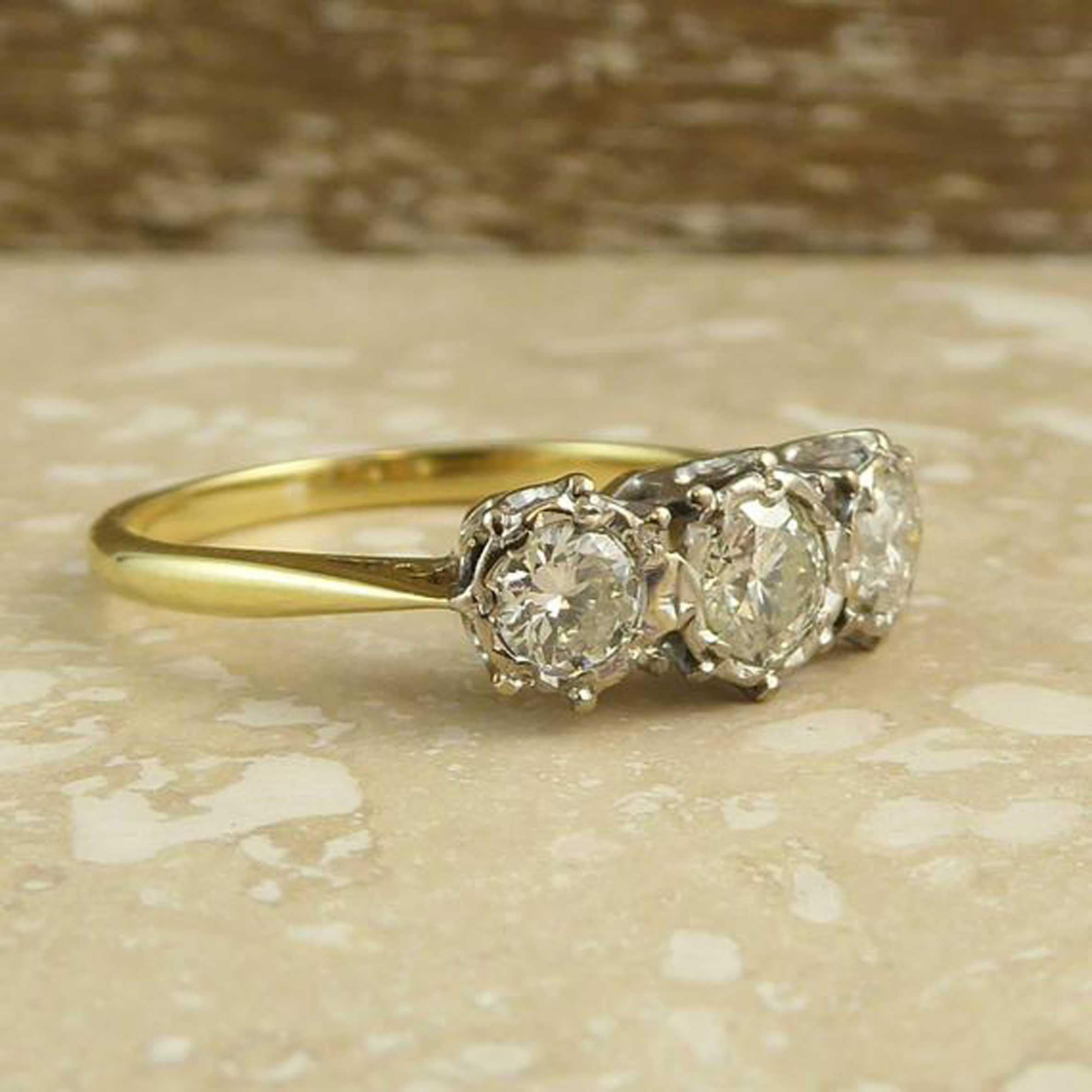 A lovely vintage 3 stone diamond engagement ring boasting three brilliant cut diamonds set in white gold surrounds and with  total carat weight of 0.50ct as stamped to the inside of the band.  This older version of the modern-day trilogy ring has a