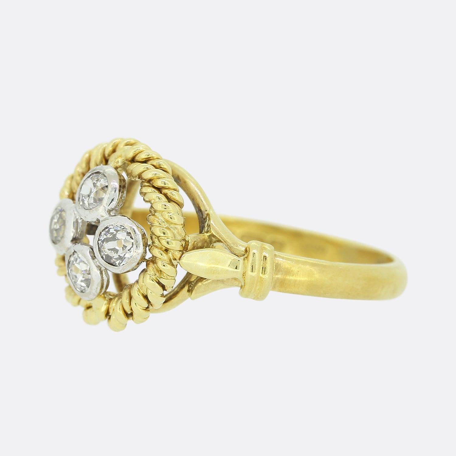 This is a vintage 18ct yellow gold diamond ring. The piece offers a quartet of old cut diamonds, each individually rub-over set in white gold at the centre of an open face. These focal stones are surrounded by a roped boarder which circulates the