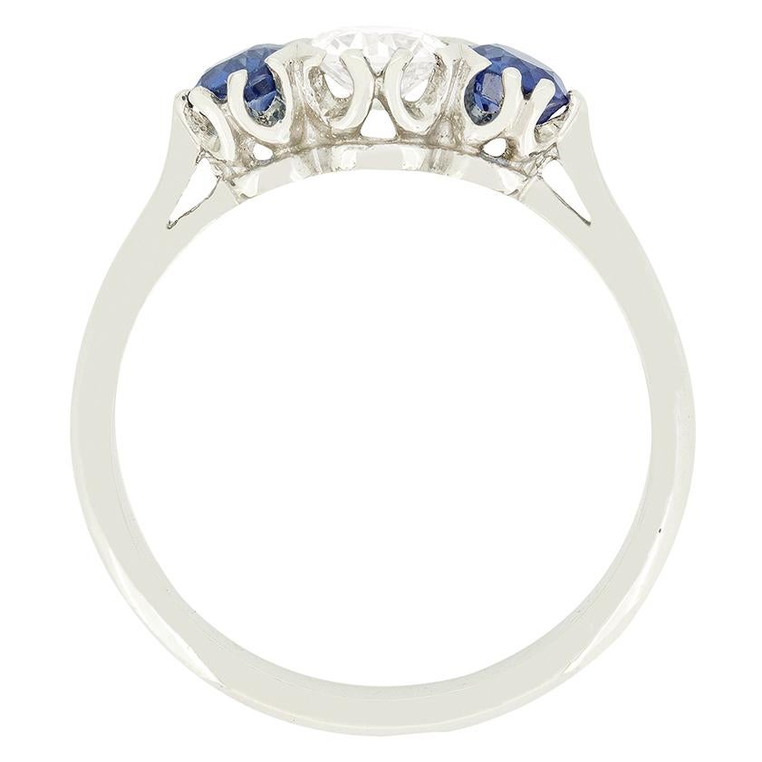 Une paire de saphirs bleus vifs encadre un diamant étincelant de taille ancienne dans ce trois pierres inversé des années 1950. Le diamant central pèse 0,50 carat et est de grande qualité, avec une couleur F et une pureté VS2. Les deux saphirs