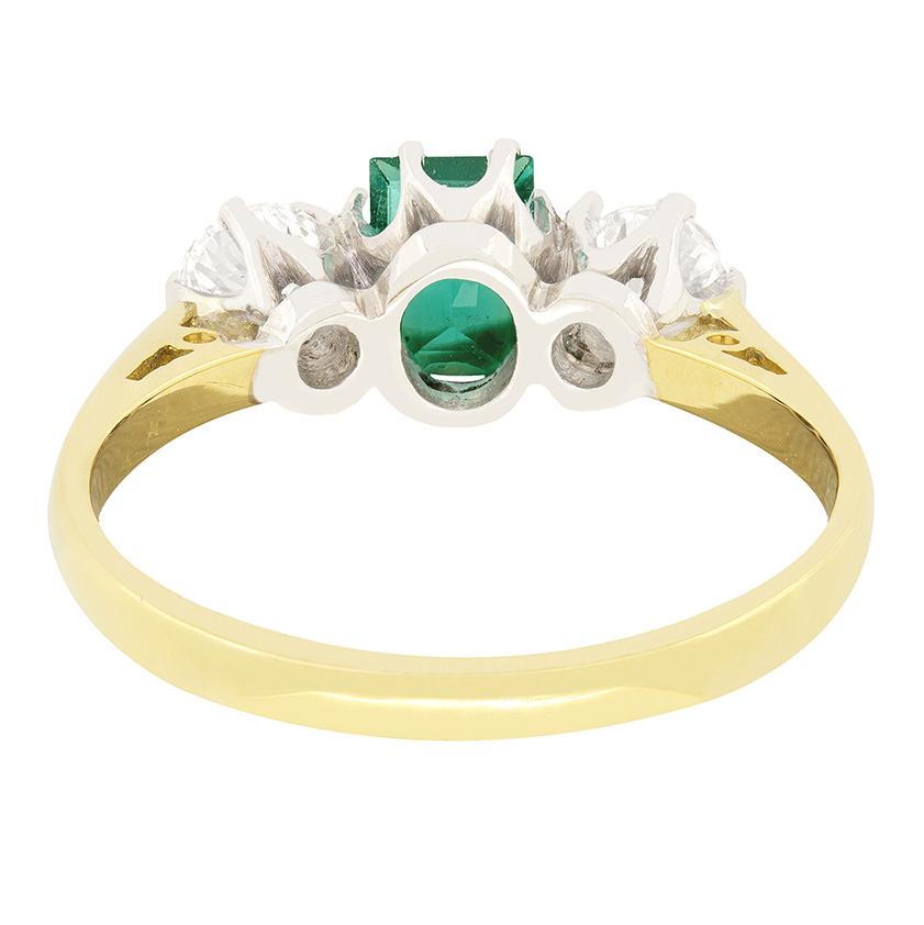 This classic Vintage trilogy ring dates to the 1980s and features a captivating 0.50 carat baguette-cut emerald at its centre, radiating with rich green hues. Flanking the emerald are two round brilliant cut diamonds, each weighing 0.25 carats. Each