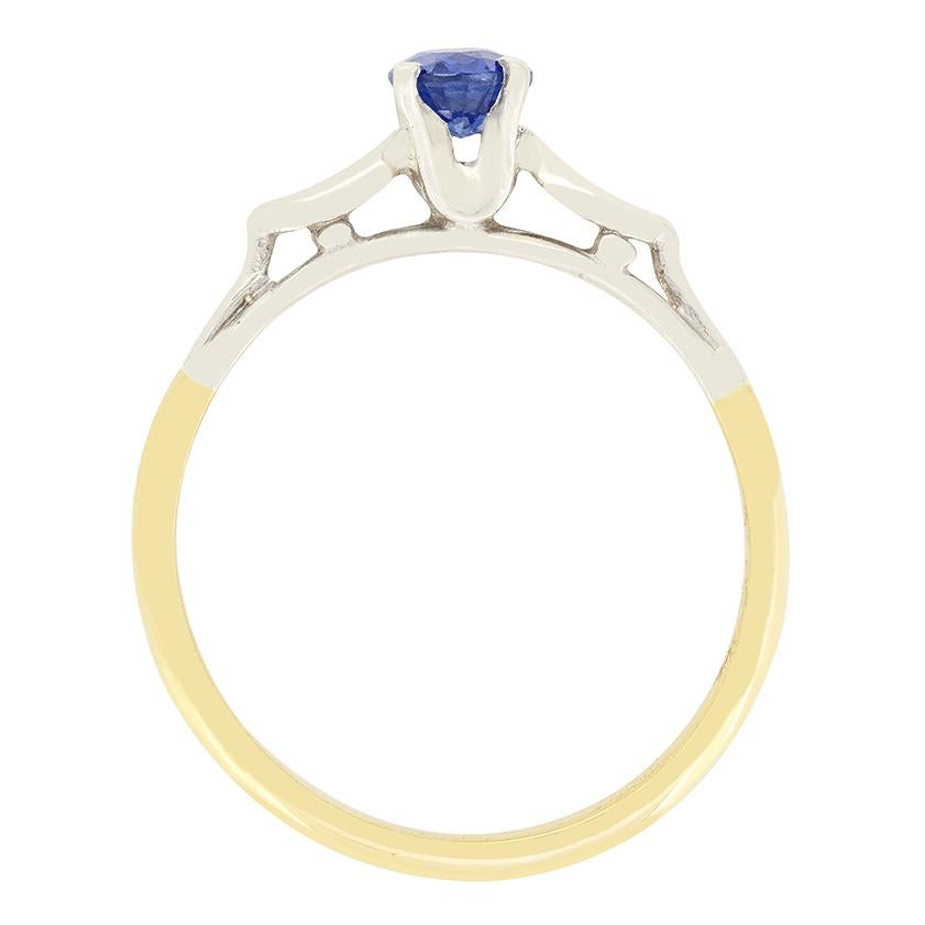 Datant des années 1950, cette magnifique bague solitaire en saphir. La pierre de taille ovale est d'un bleu vif et pèse 0,50 carat. Le saphir est serti dans un collet en or blanc 18 carats, contrastant parfaitement. Des épaulements façonnés dans le