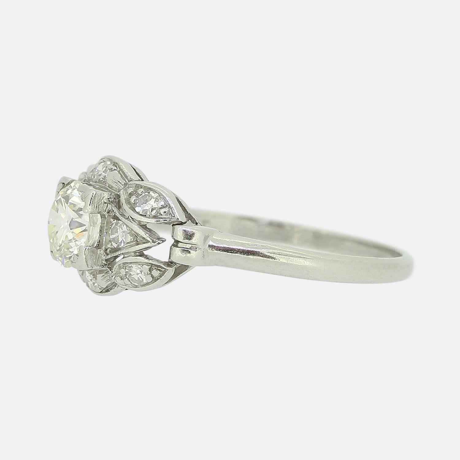 Here we have a lovely platinum diamond cluster ring. A focal 0.55ct round faceted old cut diamond sits slightly risen at the centre of the face in a four clawed setting. This piece takes on a floral-like design with multiple claw set single cut