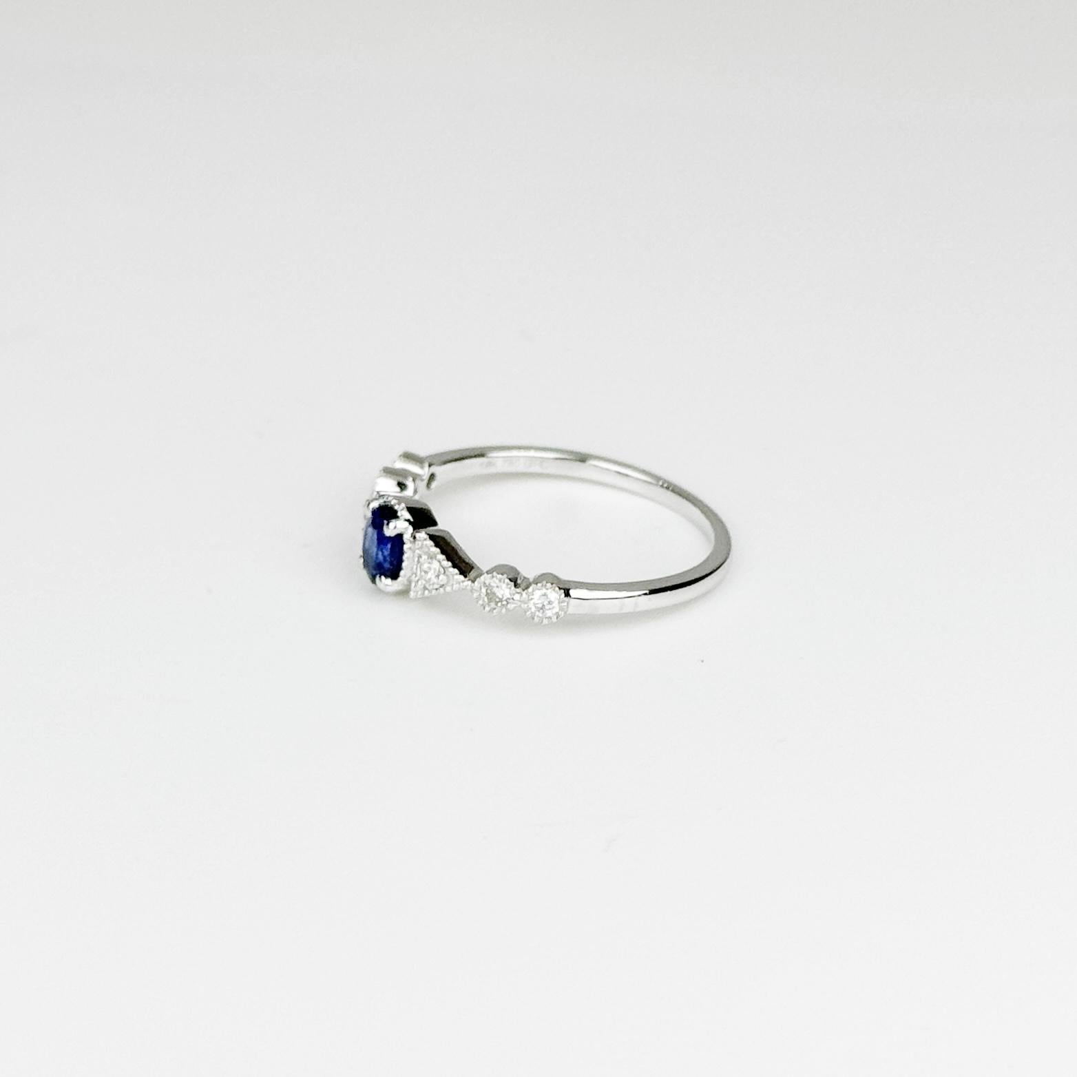 Este exquisito anillo incorpora un impresionante zafiro azul de Sri Lanka de 0,56 quilates, conocido por su tono profundo y vibrante. La piedra central se complementa elegantemente con diamantes de 0,13 quilates, de color G-H y claridad SI, que