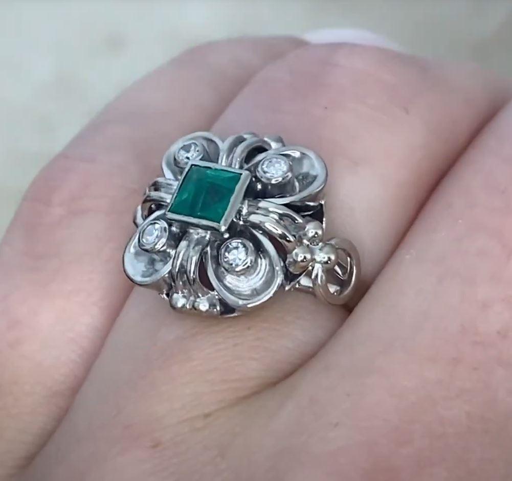 This exquisite vintage ring showcases a stunning square-cut emerald at the center, weighing approximately 0.6-carats. The rich, deep green hue of the emerald is beautifully highlighted by the surrounding intricate design, making this piece a true