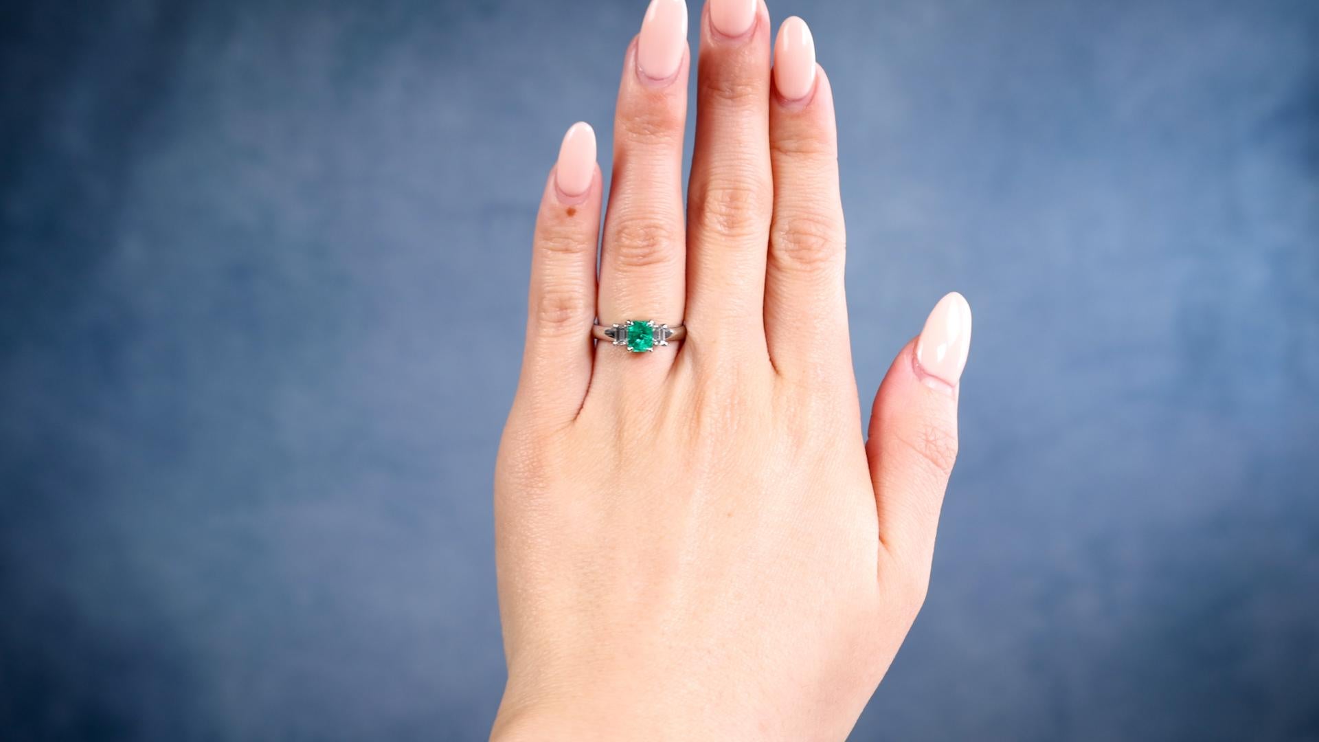 One Vintage 0.69 Carat Emerald and Diamond Platinum Three Stone Ring. Featuring one octagonal step cut emerald of 0.69 carat. Accented by two emerald cut diamonds with a total weight of 0.32 carat, graded F color, VS clarity. Crafted in platinum