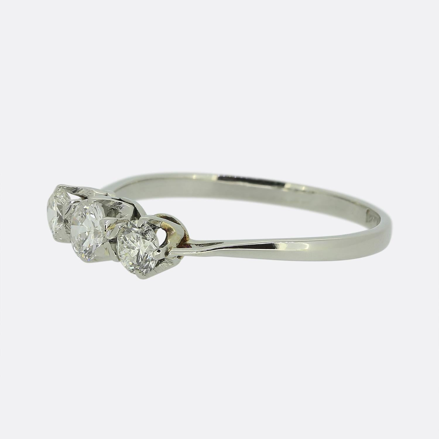 Nous avons ici une bague à trois pierres de style classique. Fabriquée en platine, la bague est ornée d'un diamant rond de 0,30 carat de taille brillant et d'une pierre légèrement plus petite de part et d'autre. Tous les diamants ont été sertis
