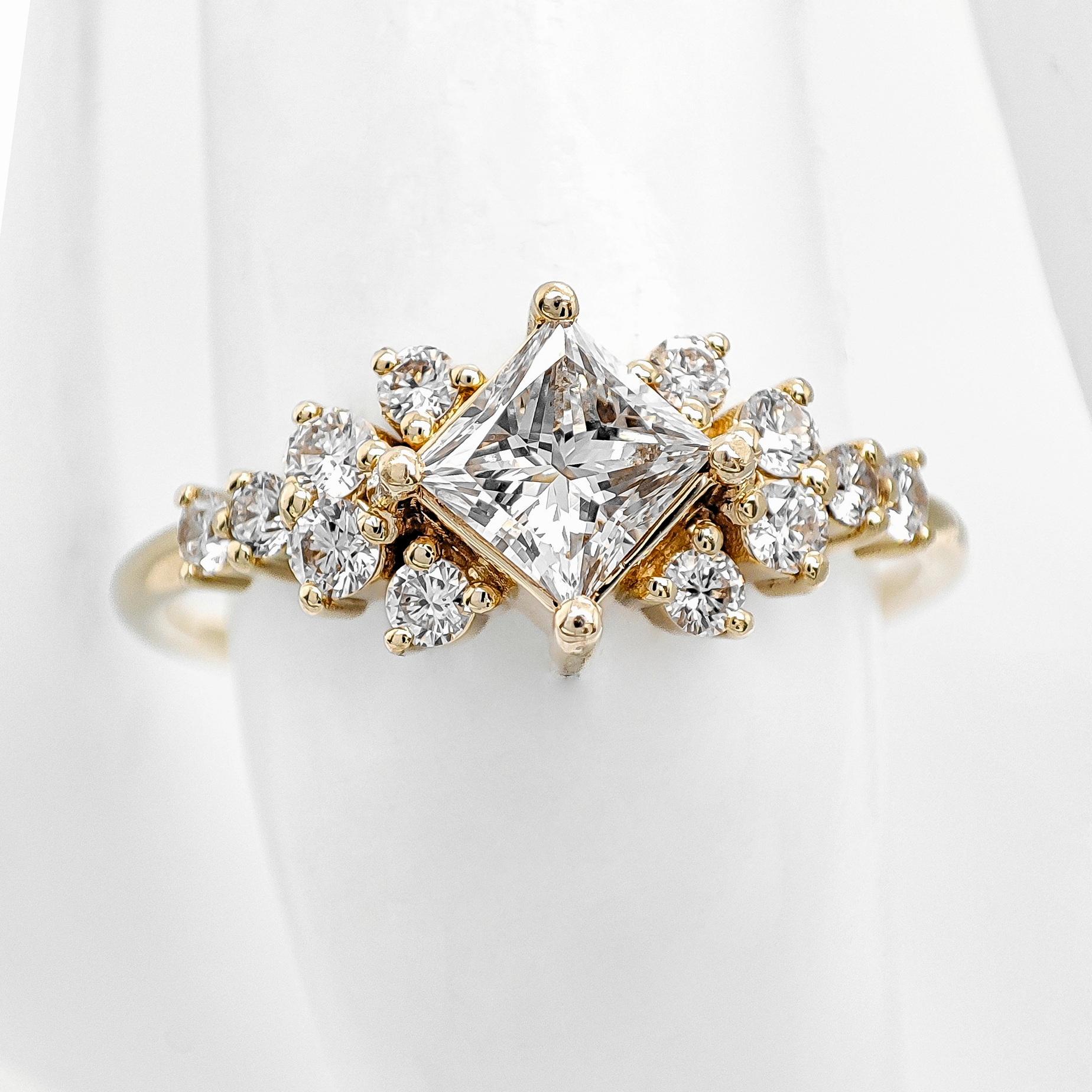 FOR U.S. BUYERS NO VAT NO CUSTOMS FEES

This stunning ring showcases a central natural diamond, expertly cut into a princess cut, with a weight of 0.40 carats and a warm F color, radiating elegance and charm. Surrounding it are 12 side diamonds,