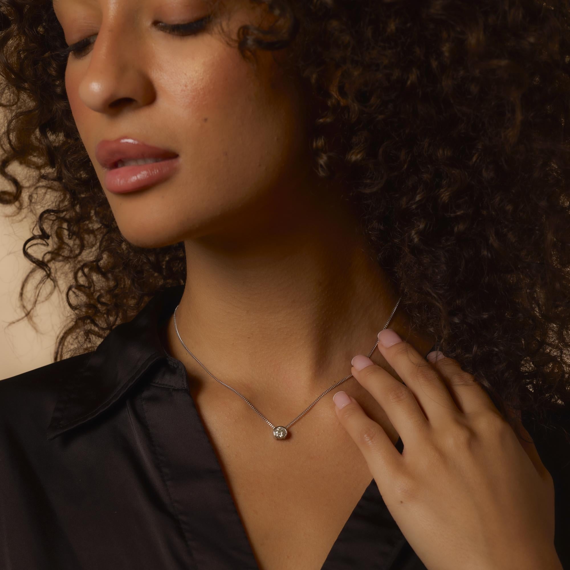 This vintage platinum necklace highlights a .75 carat round brilliant diamond, offering soft sparkle in an elegant design with a refined white gold clasp.