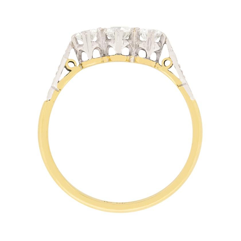Este dulce anillo de compromiso presenta tres diamantes redondos de talla brillante. El diamante central es de 0,35 quilates, mientras que las dos piedras laterales son de 0,20 quilates cada una. Están engastadas en platino. Los hombros tienen un