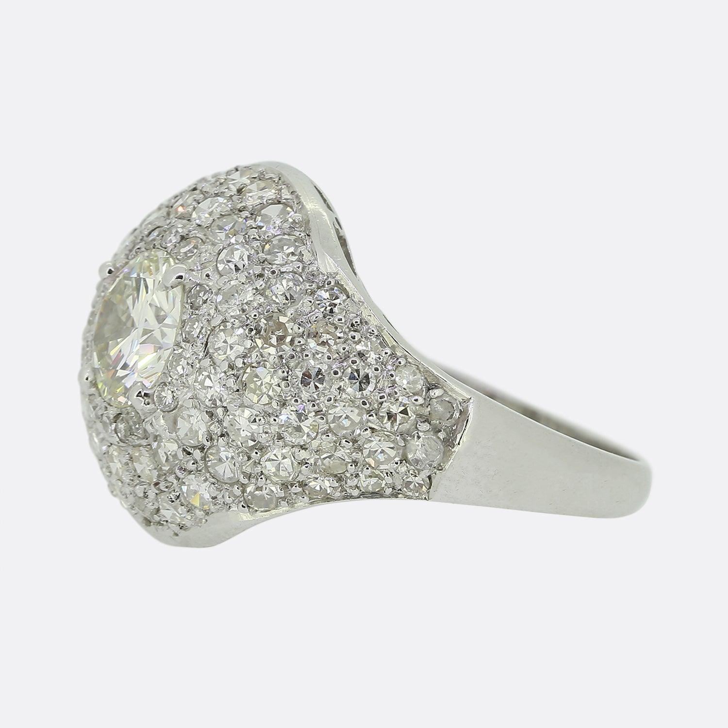 Here we have a scintillating vintage diamond bombe ring excellently exemplifying a style which was popularised in the 1920s. This ring features a centralised round brilliant cut diamond in a four clawed setting at the centre of the face. This