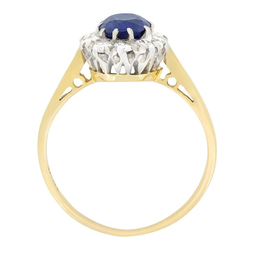 Un bellissimo zaffiro blu è al centro di questo anello a grappolo degli anni Cinquanta. La pietra dal taglio ovale pesa 0,90 carati ed è sapientemente incastonata nel platino. Intorno allo zaffiro scintilla un'aureola di diamanti tondi brillanti.