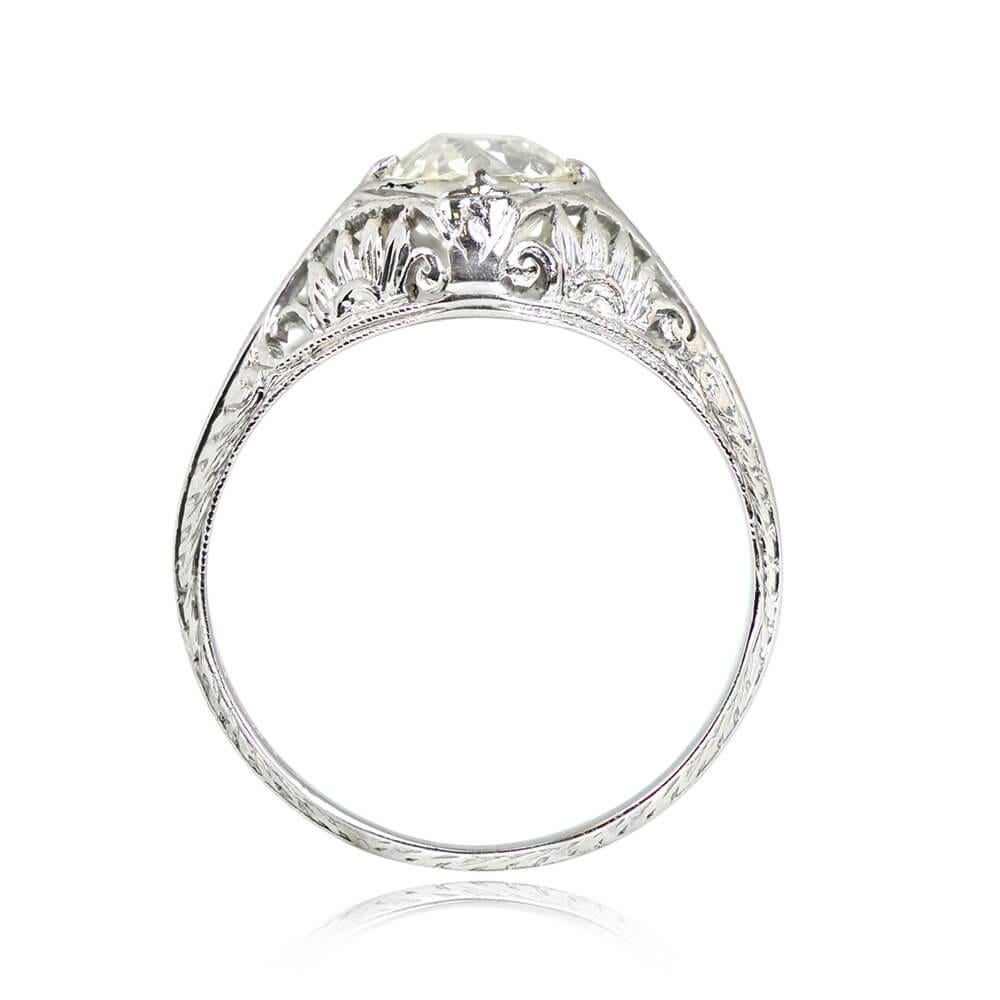An Art Deco engagement ring showcases a prong-set 0.93-carat old European cut diamond, K color, and VS1 clarity. The dome-shaped mounting boasts floral openwork on the under-gallery and fine milgrain detailing. Hand engravings adorn the shoulders,