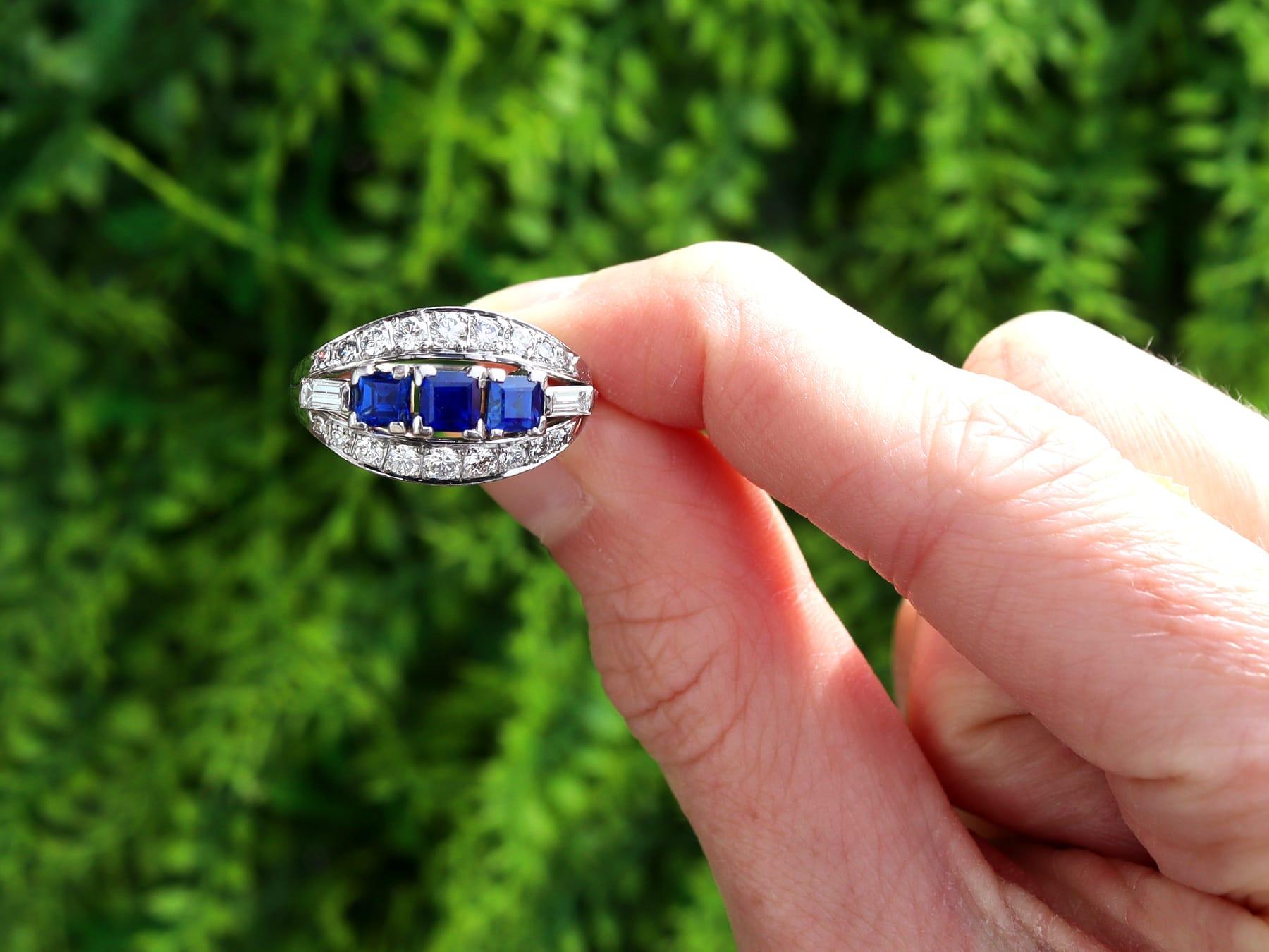 Dieser atemberaubende, feine und beeindruckende Ring mit blauem Saphir und Diamanten im Vintage-Stil wurde aus 18 Karat Weißgold gefertigt.

Die durchbrochene, verzierte Ringfassung ist mit drei blauen Saphiren mit quadratischem Facettenschliff von