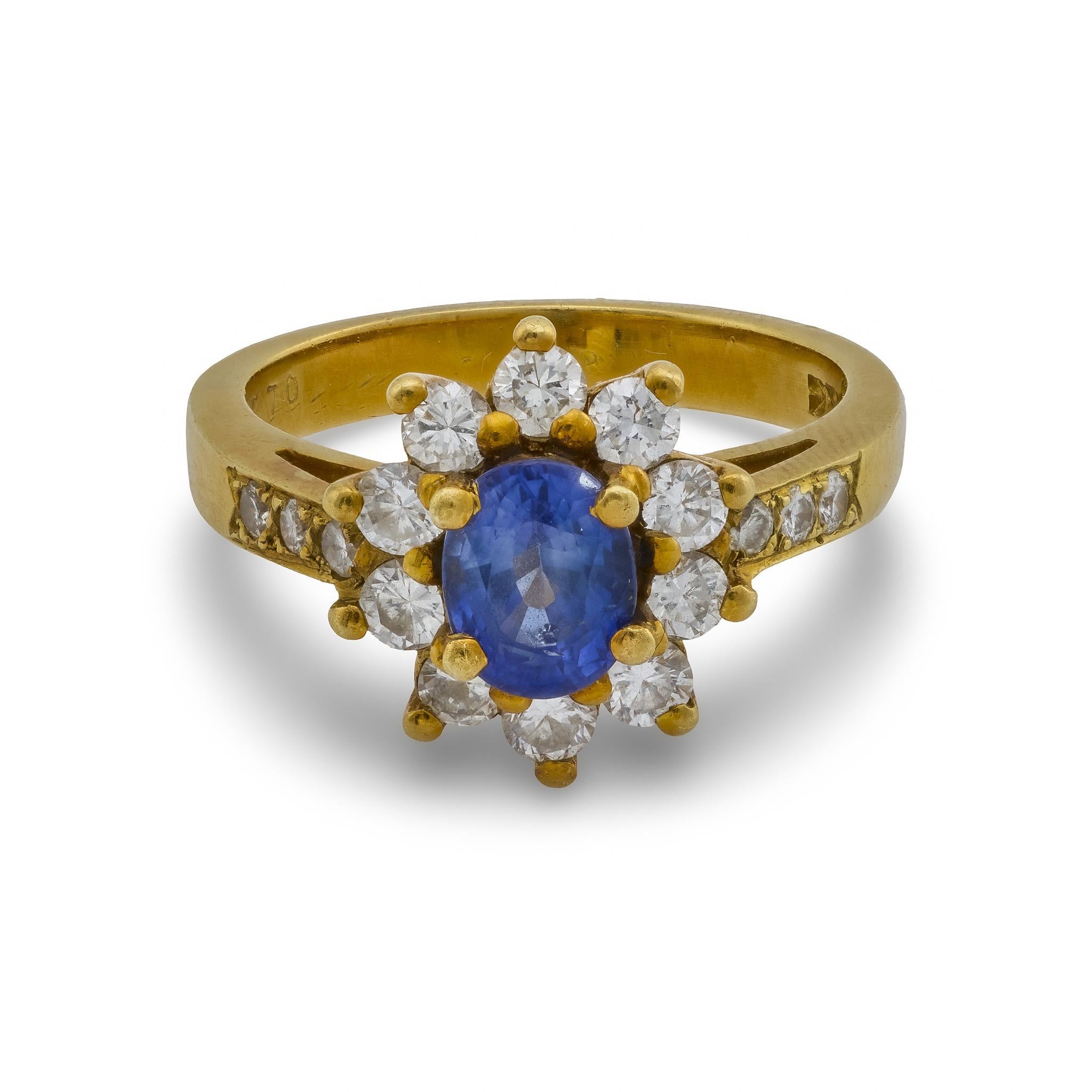 Une captivante bague vintage en or jaune 18 carats mettant en valeur un saphir ovale de 1 carat, encadré par 16 diamants étincelants de couleur G-H et de pureté SI, pour une élégance intemporelle.
