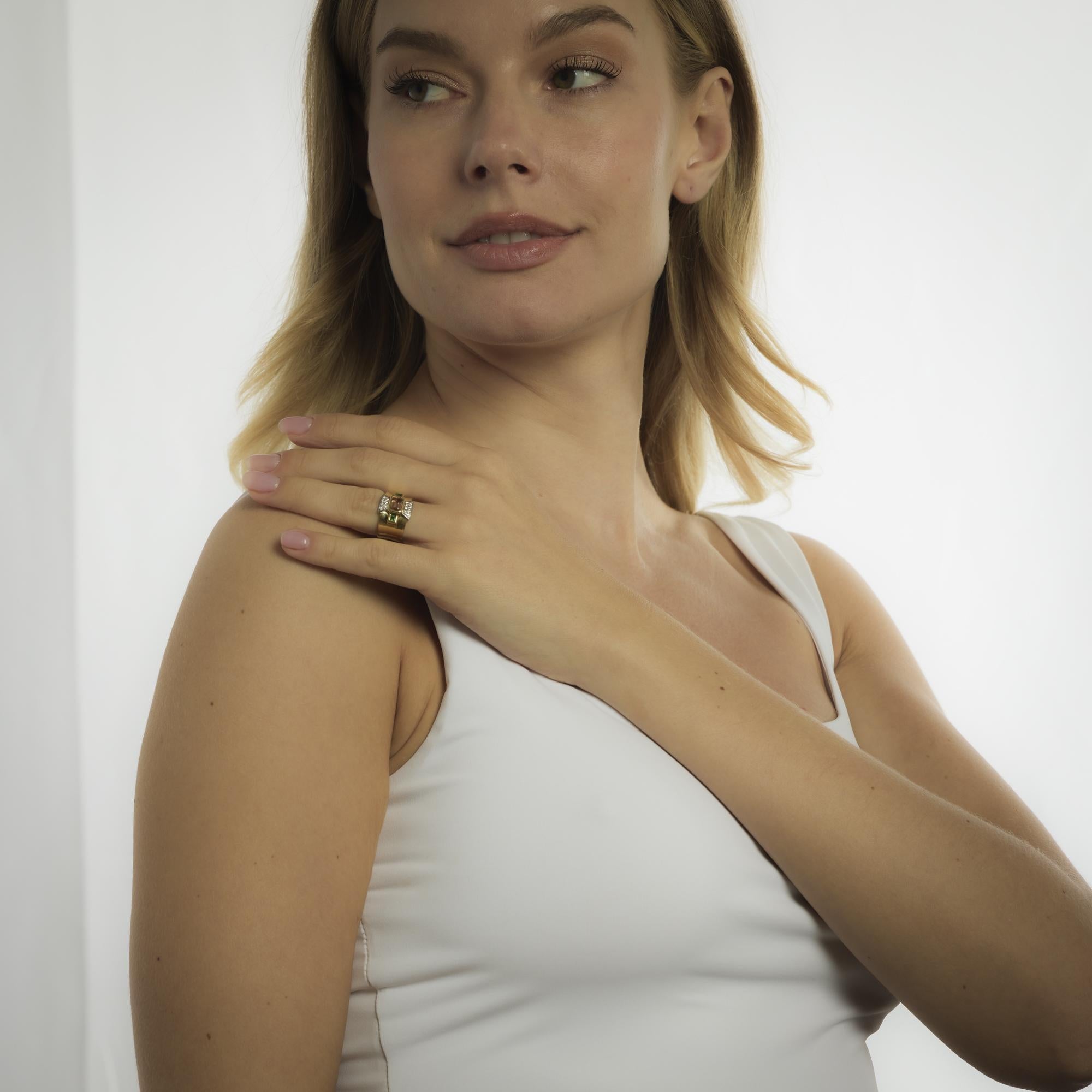 Este anillo vintage de oro amarillo de 18 quilates de la década de 1980 se centra en un vibrante topacio naranja talla esmeralda de 1,00 quilate, flanqueado por dos turmalinas talla baguette que suman aproximadamente 0,20 quilates. Catorce diamantes