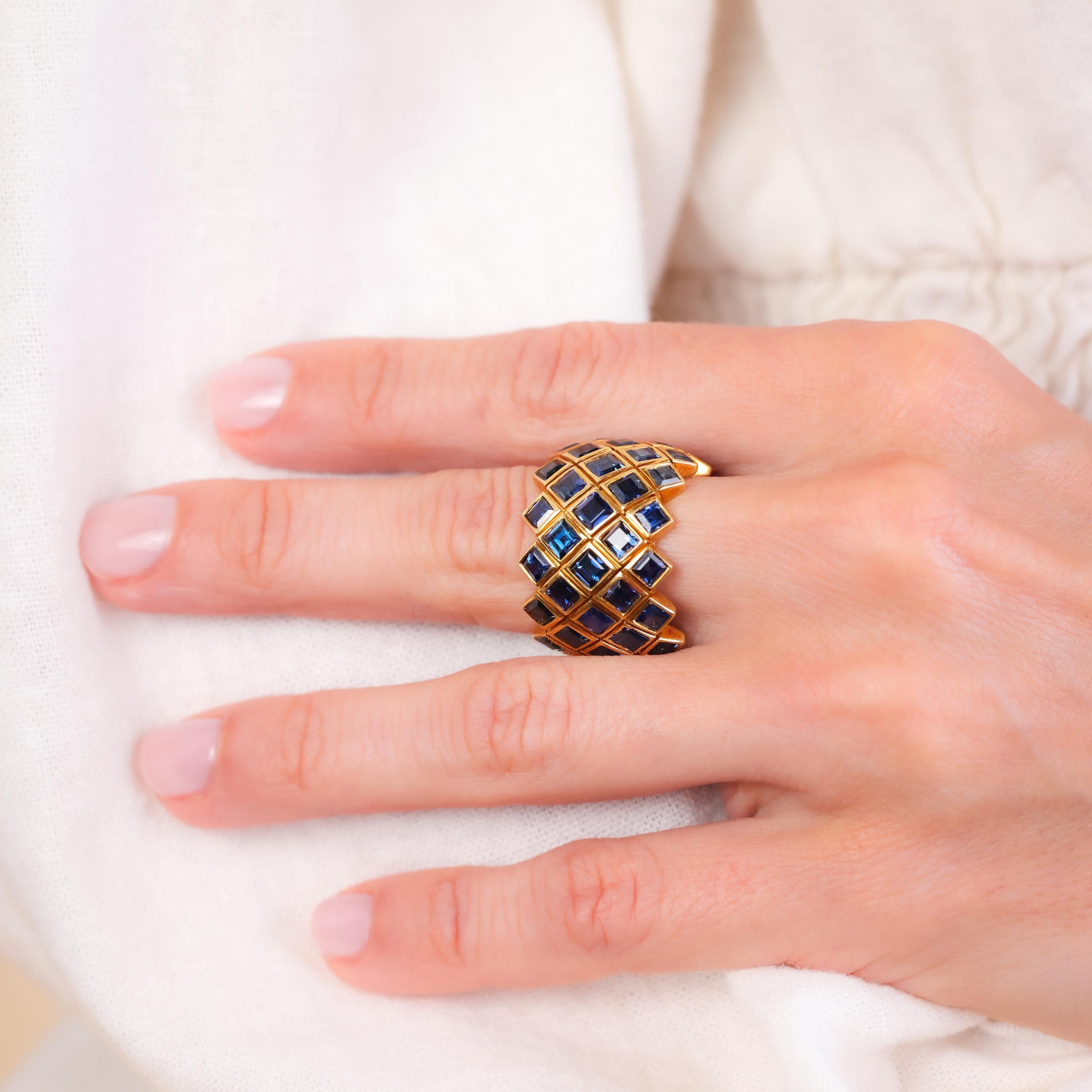 Center Stone: 50 Sapphires
Cut: Carre
Weight: Approximately 10 Carats
Color: Blue
Metal: 18K Yellow Gold
Era: Vintage
Circa: 1980s
Size: 6.5
Gram weight: 13.79

This striking vintage ring from the 1980s is adorned with 50 carre-cut blue sapphires,